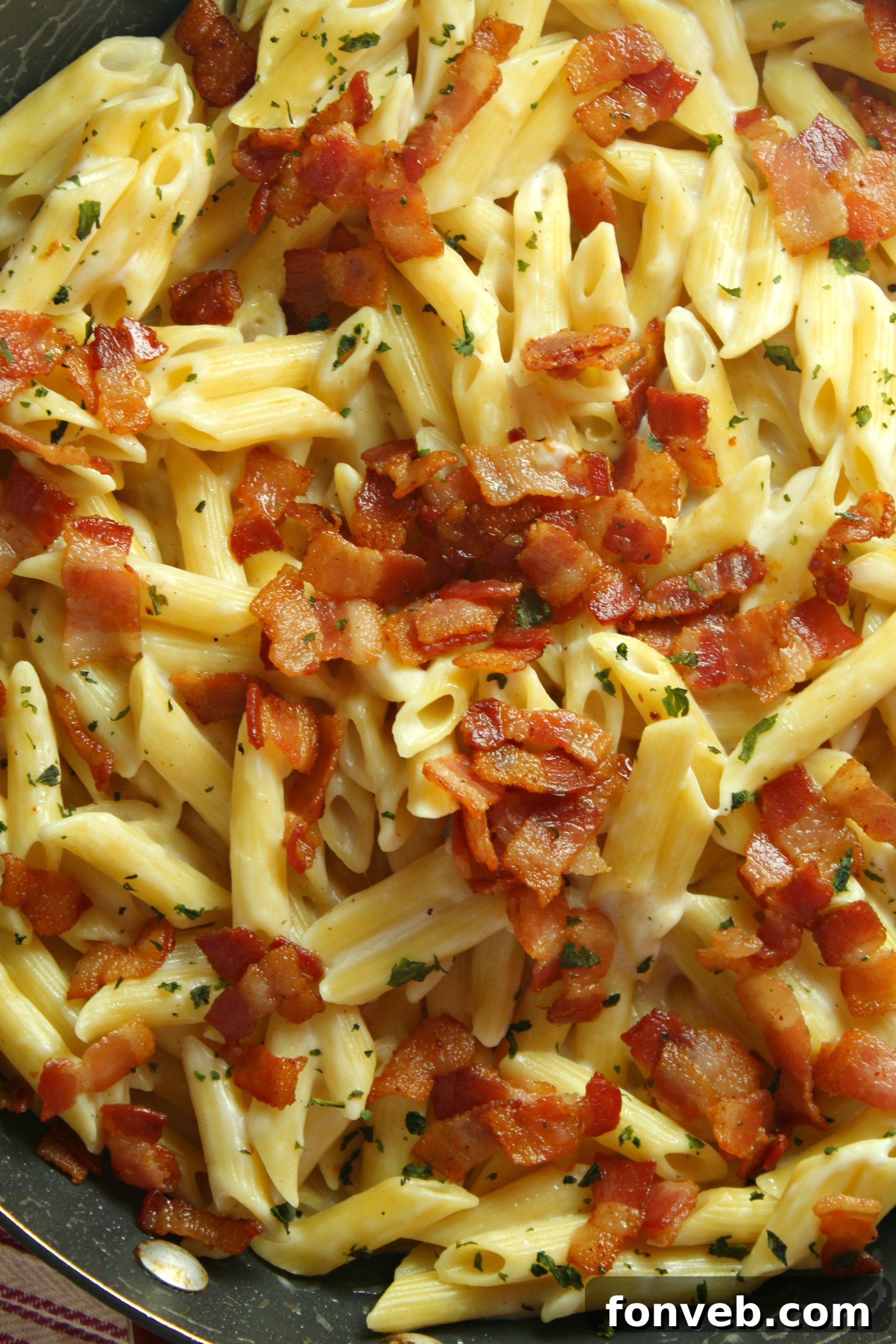 A wide shot of a large serving of creamy bacon alfredo pasta in a bowl, ready to be enjoyed.
