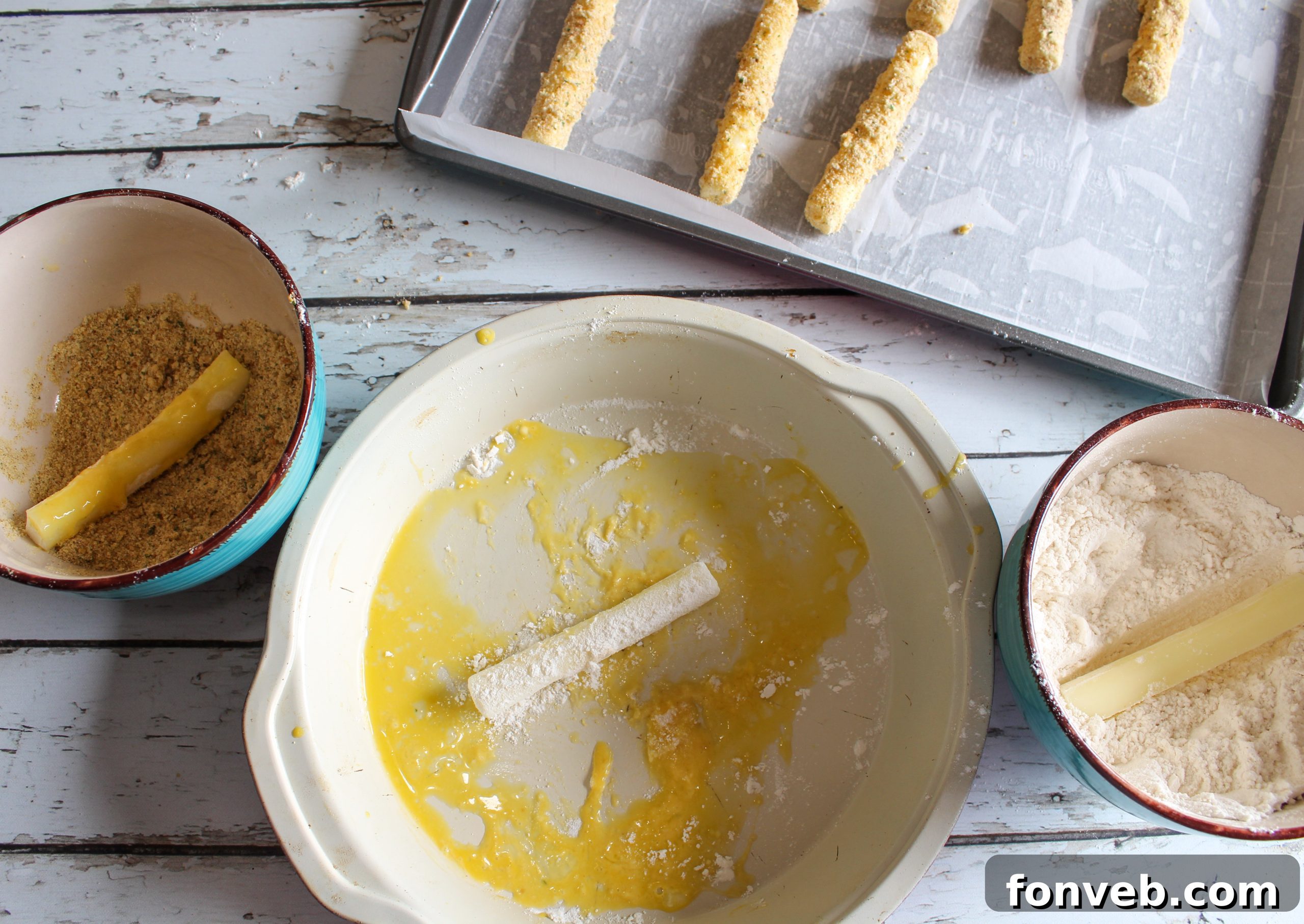 Three prepared Air Fryer Mozzarella Sticks arranged with a dipping bowl of marinara sauce.