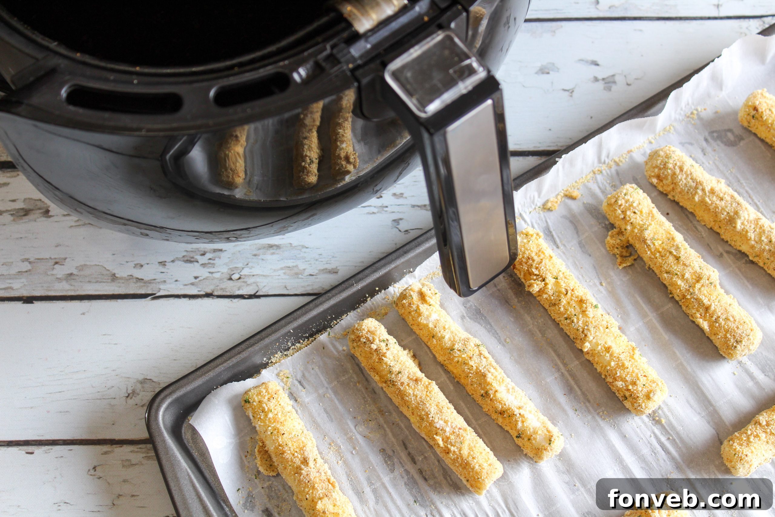 A top-down shot of a variety of Air Fryer Mozzarella Sticks, some broken open to show the melted cheese.