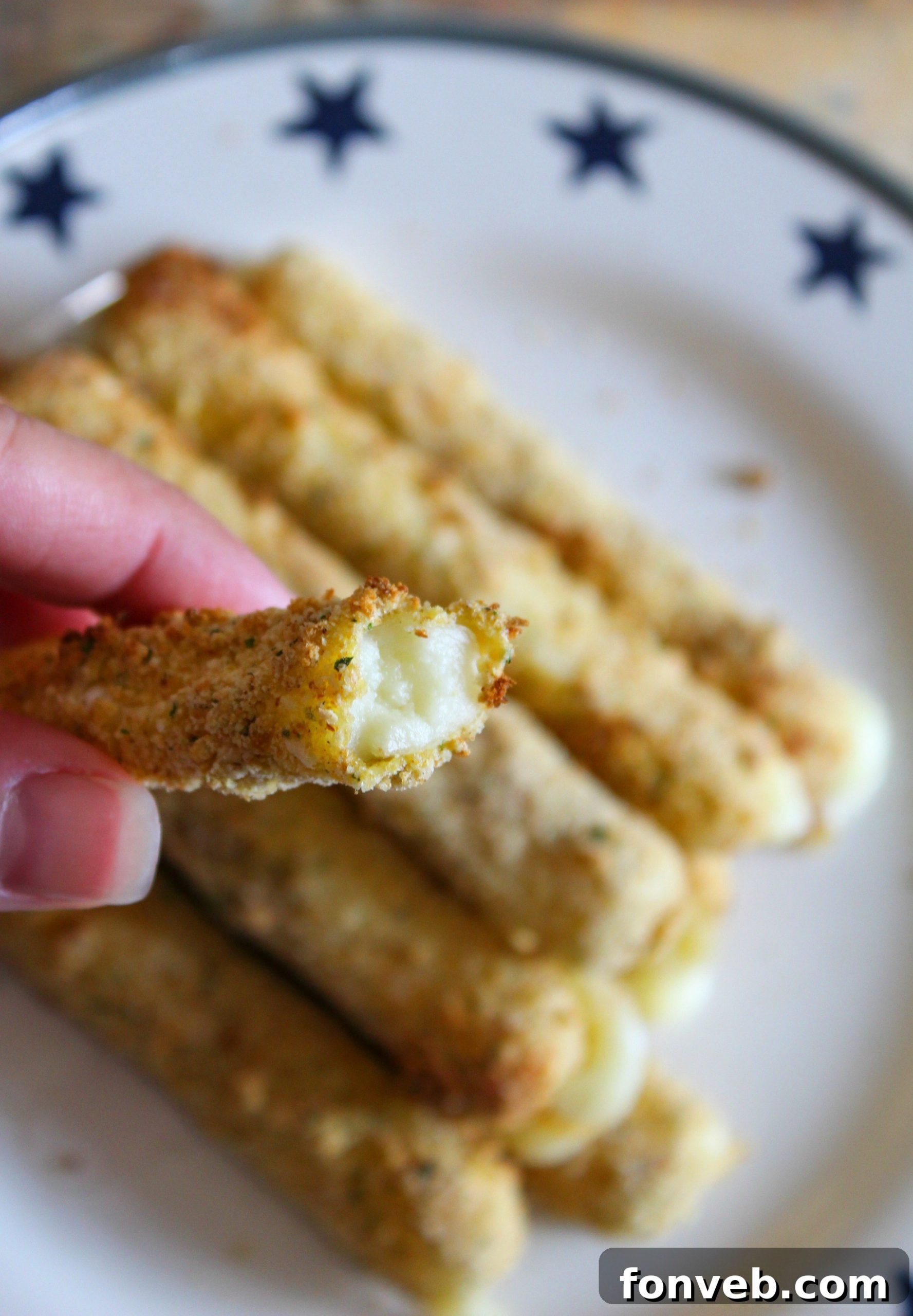 Several golden Air Fryer Mozzarella Sticks on a plate with a vibrant red marinara dipping sauce.