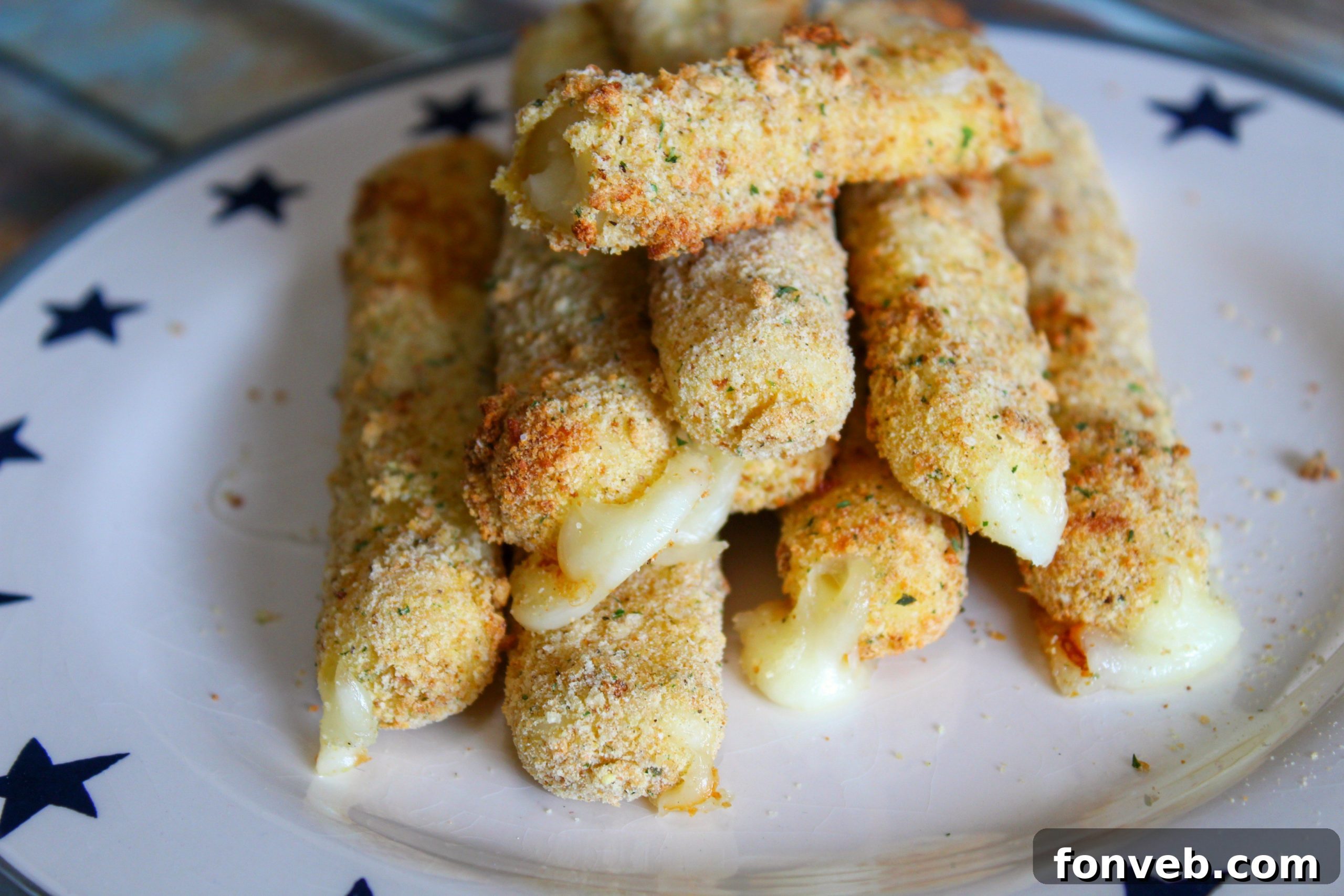 An array of Air Fryer Mozzarella Sticks artfully arranged on a serving plate with a small bowl of marinara for dipping.