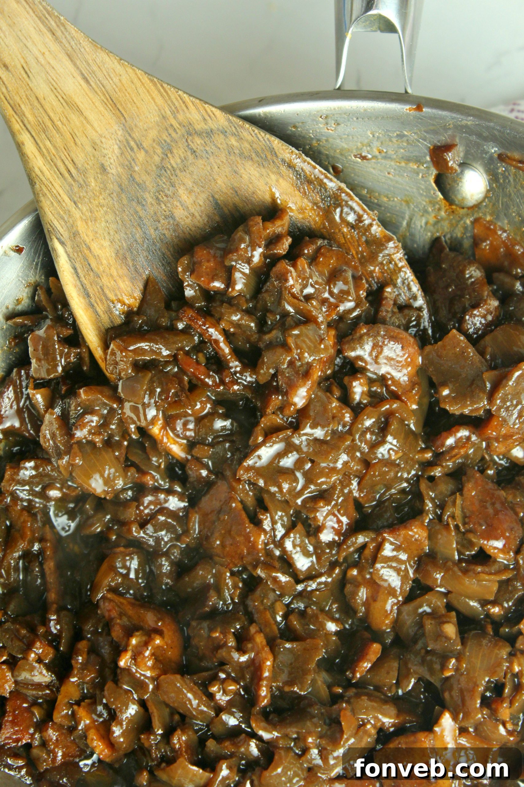 Homemade bacon jam spread generously on a cracker with a slice of cheese, ready to be served as an appetizer.