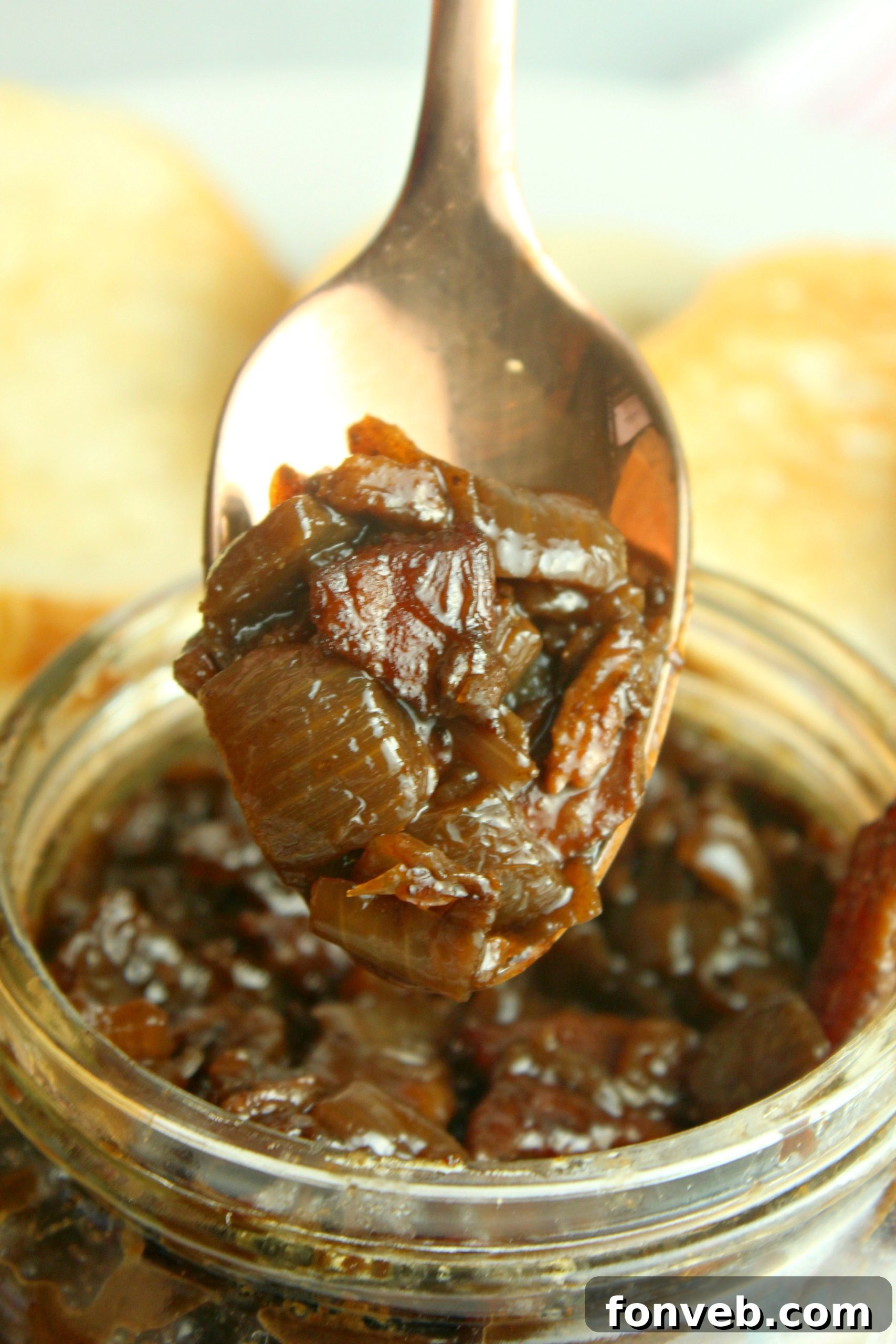 A serving of bacon jam carefully spread onto a piece of toasted bread, showcasing its rich texture.