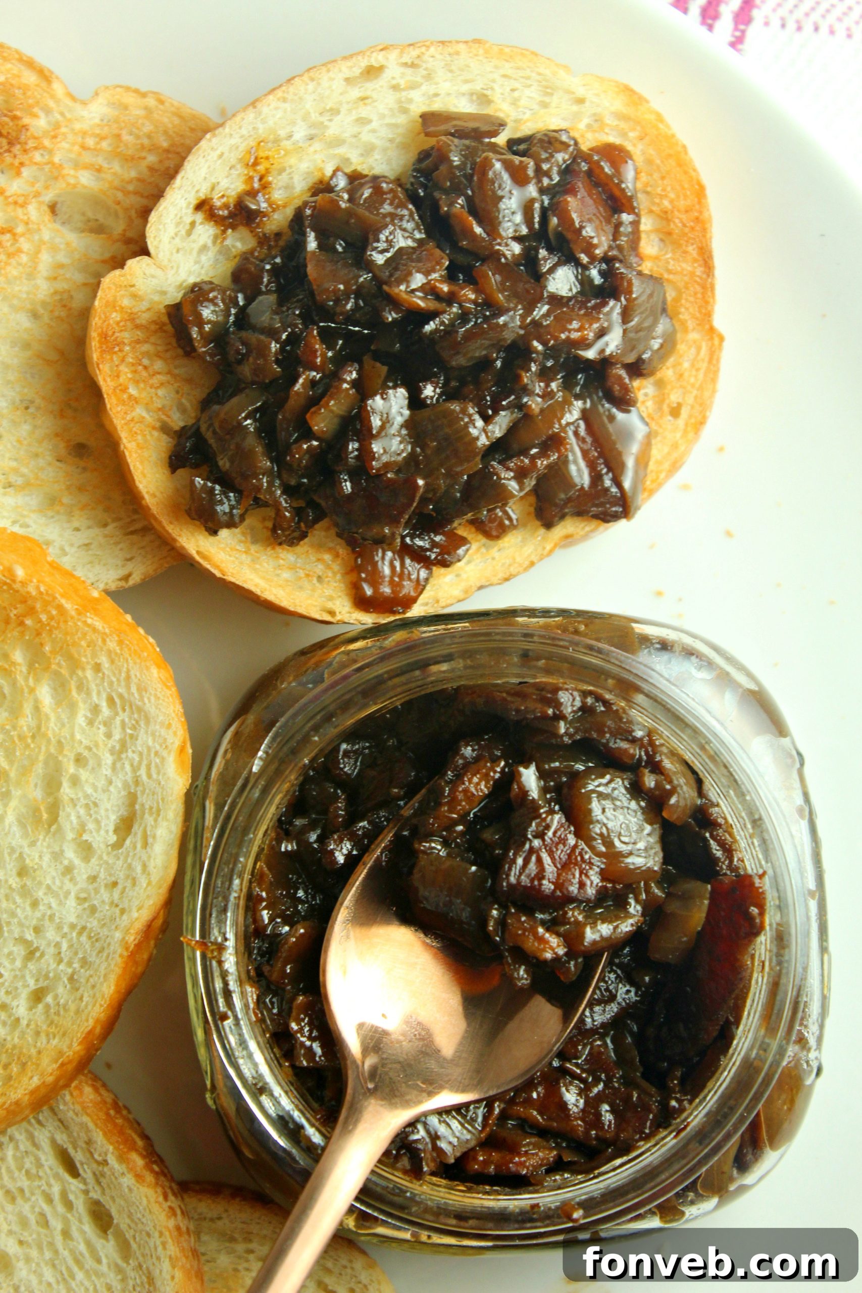 Crispy, thick-cut bacon strips laid out on a paper towel-lined plate, cooling after being cooked for the jam.