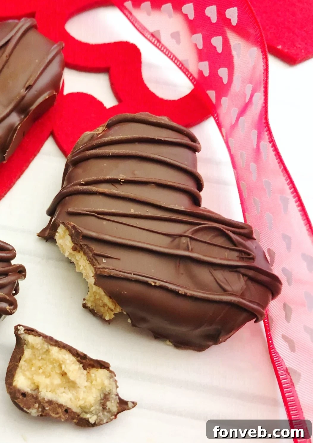 Dipped peanut butter hearts on parchment paper, showing the smooth chocolate coating