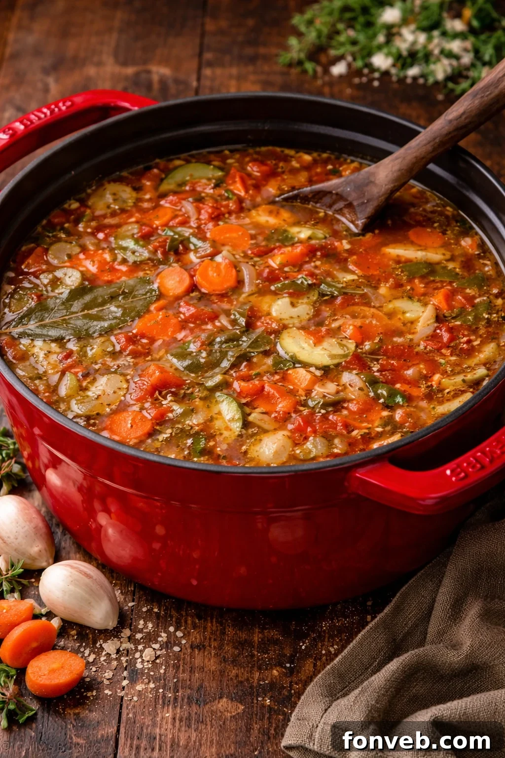 Weight loss soup in a red dutch oven pot on a dark wood table with a wooden spoon in it 