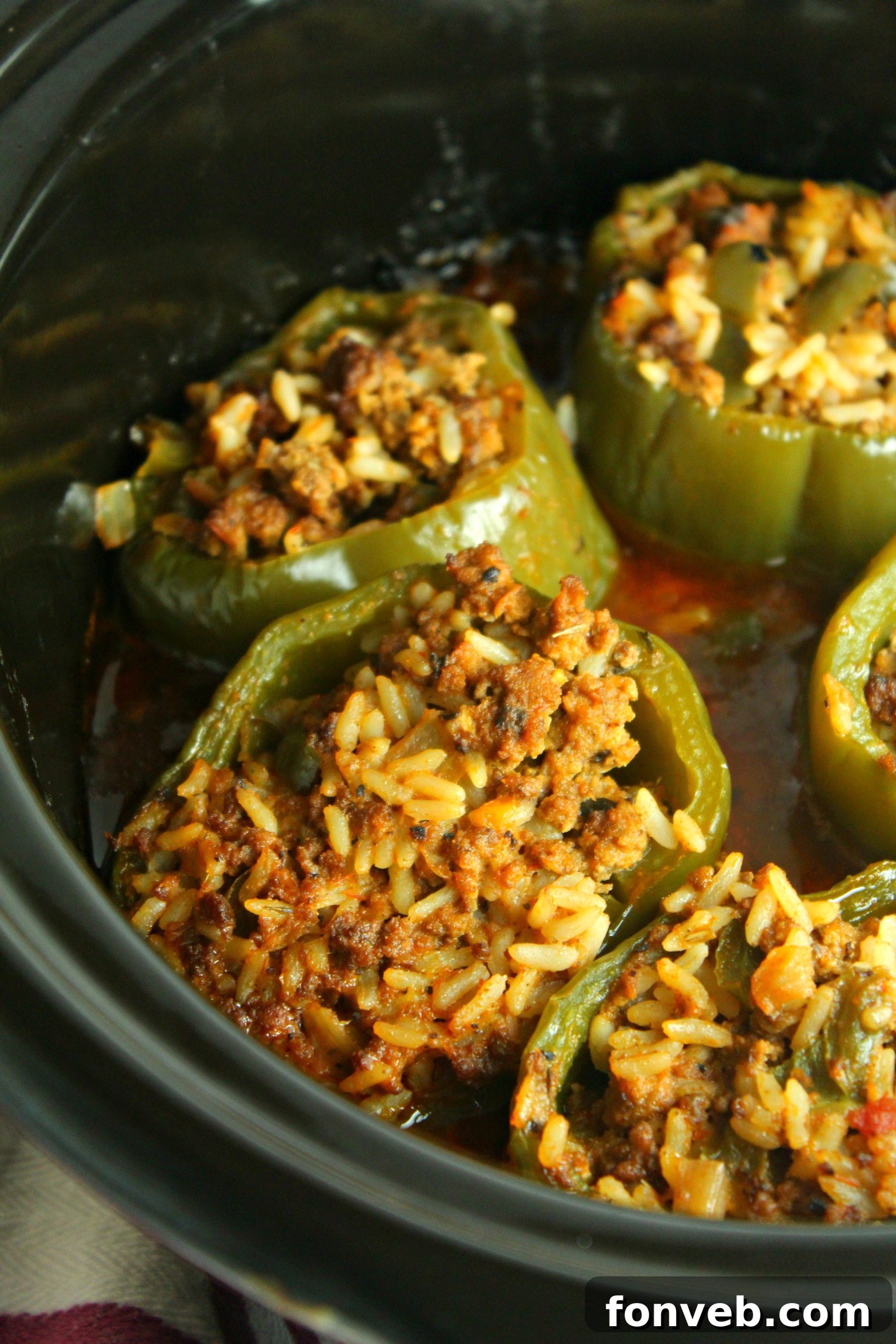 Ingredients for Slow Cooker Stuffed Peppers laid out on a cutting board: ground beef, rice, bell peppers, onion, garlic, and spices.