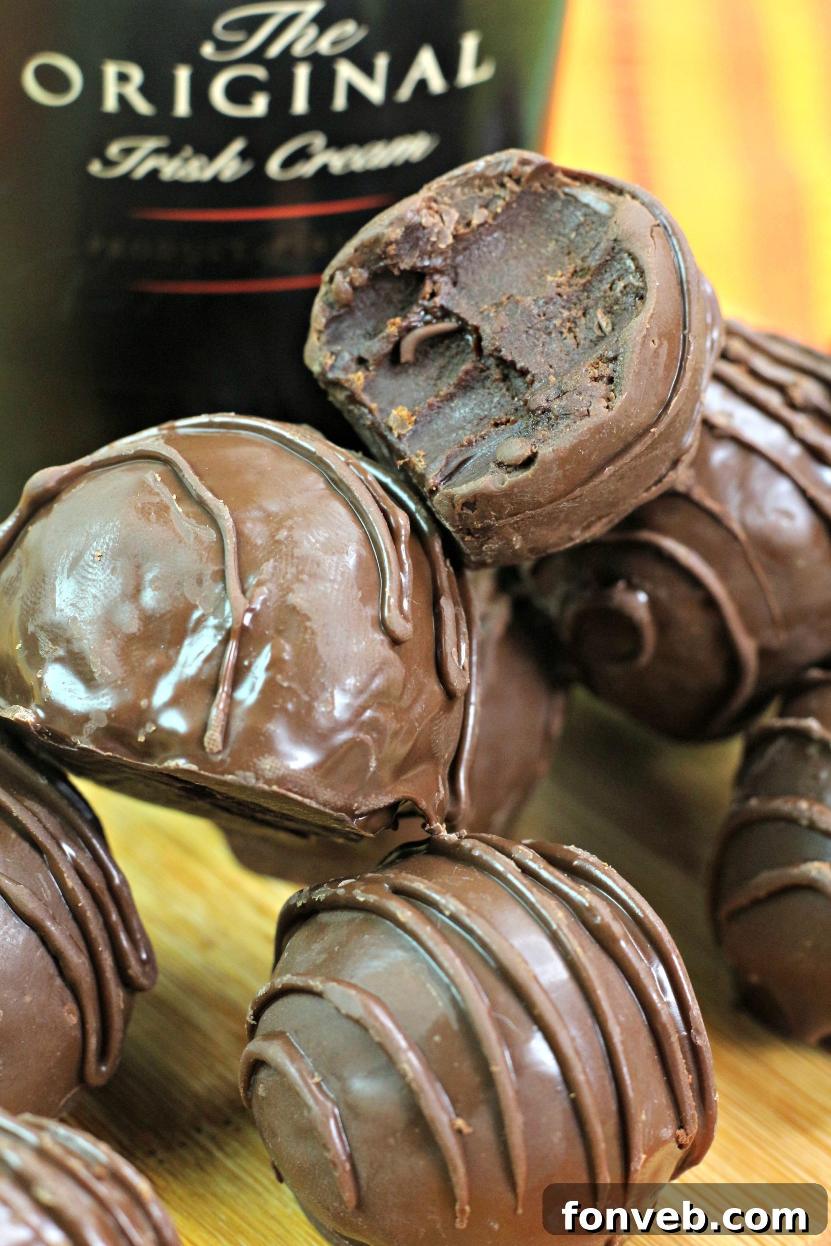 Close-up of a perfectly rolled Bailey's Irish Cream truffle, showcasing its smooth, glossy chocolate coating.