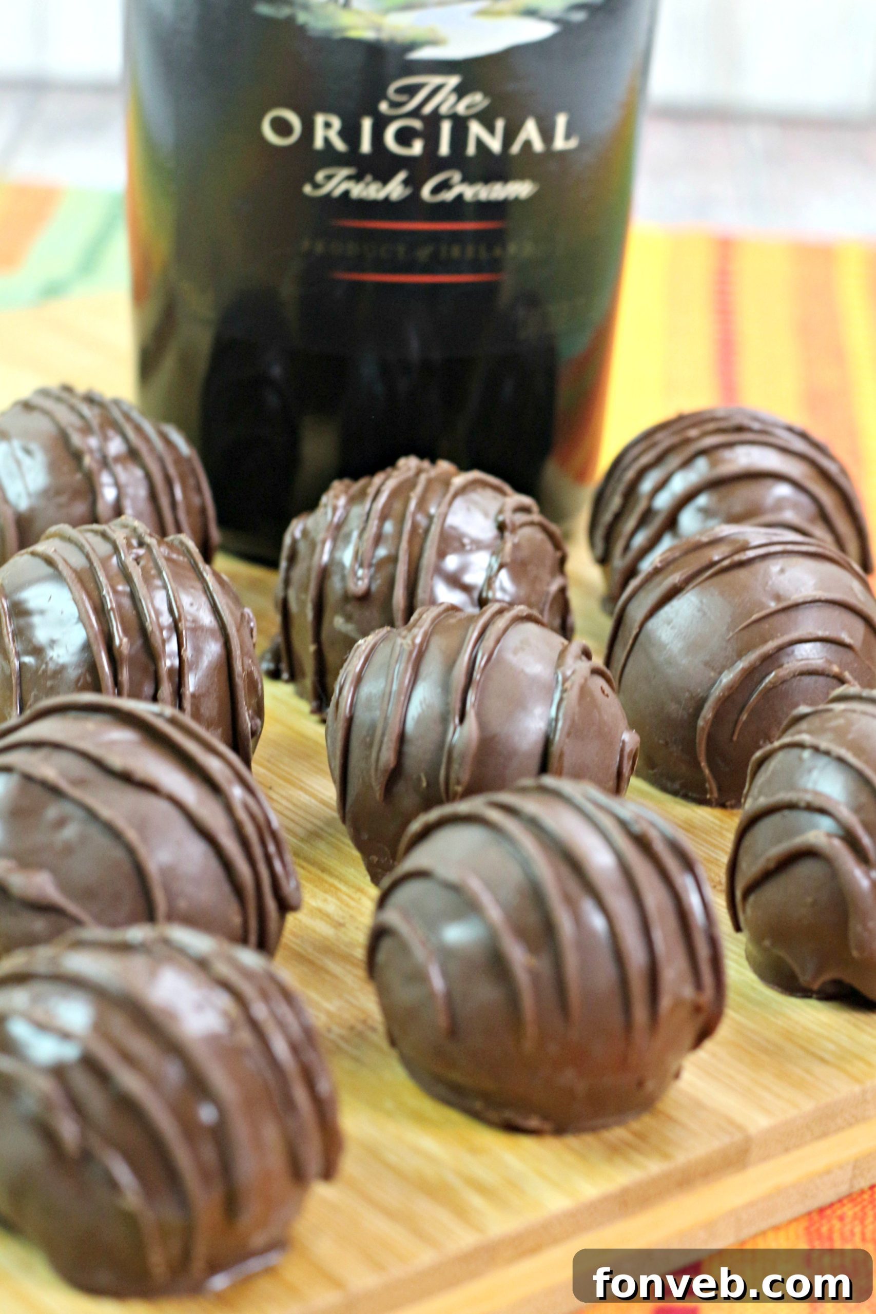 Hands carefully rolling chocolate ganache into small, perfectly round balls on a baking sheet, ready for coating.