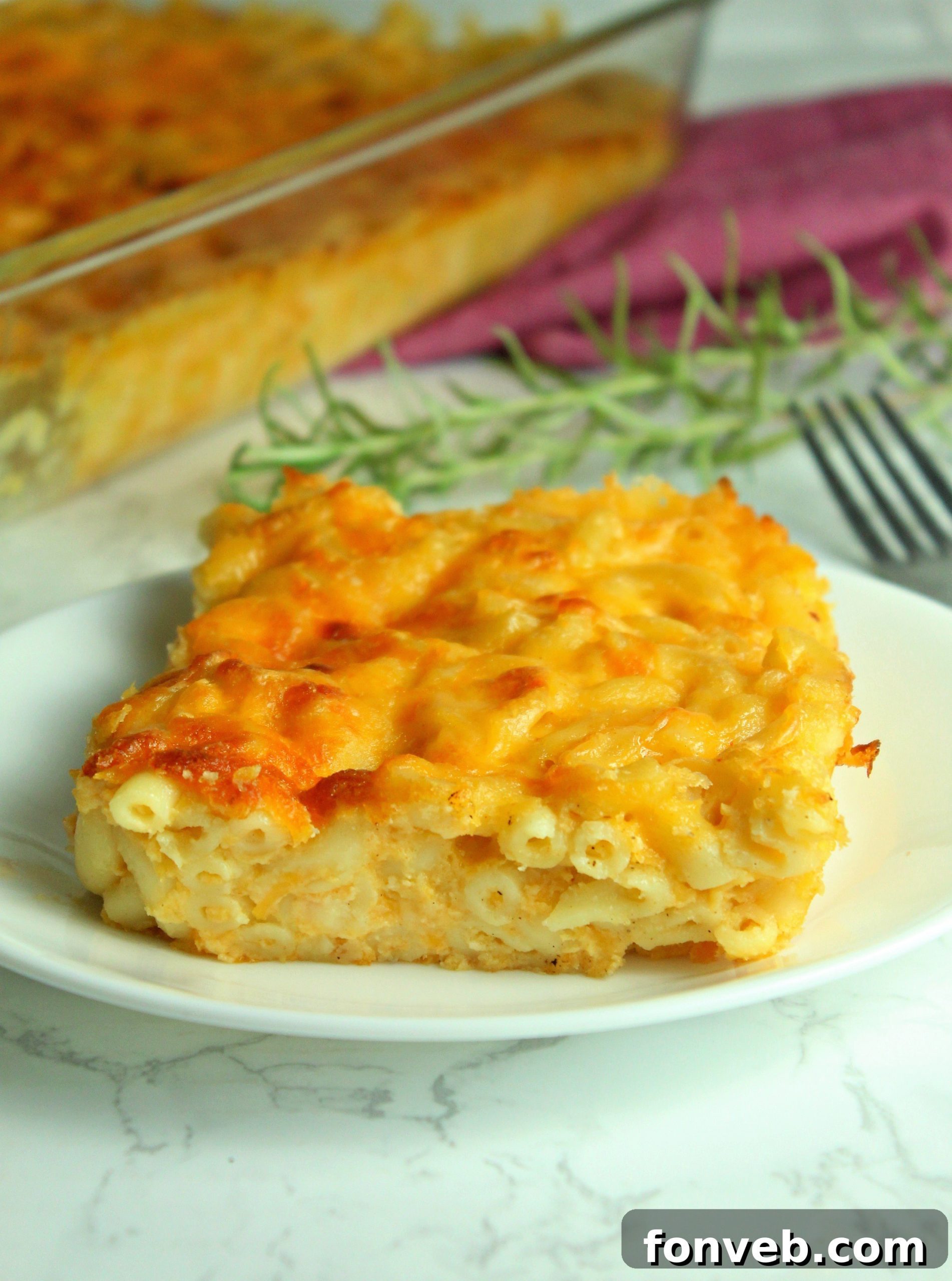 A close-up of a fork scooping into the creamy, stretchy Southern Baked Macaroni & Cheese, revealing the molten interior and the delicious pasta.