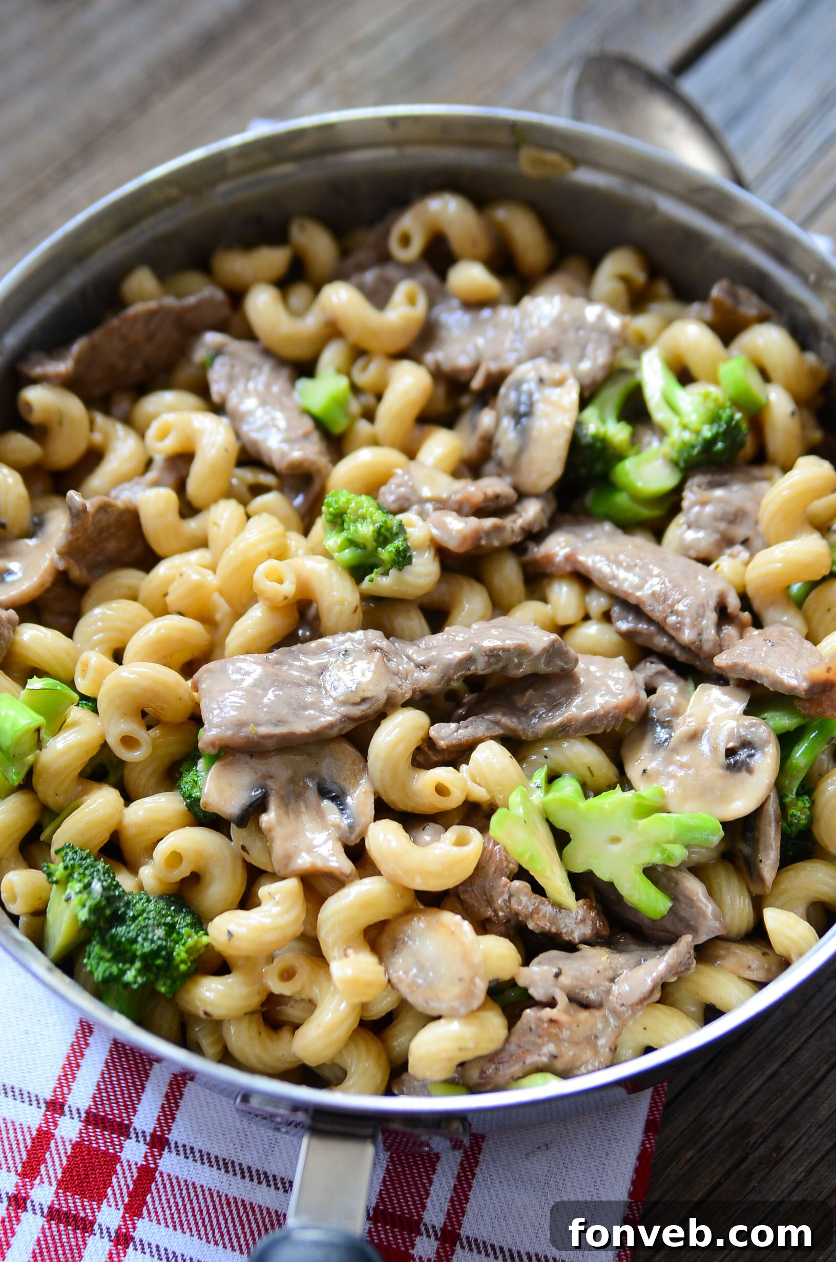 Hearty Beef, Mushroom & Broccoli Pasta 5 Assorted ingredients for Beef, Mushroom, and Broccoli Pasta laid out on a wooden cutting board.