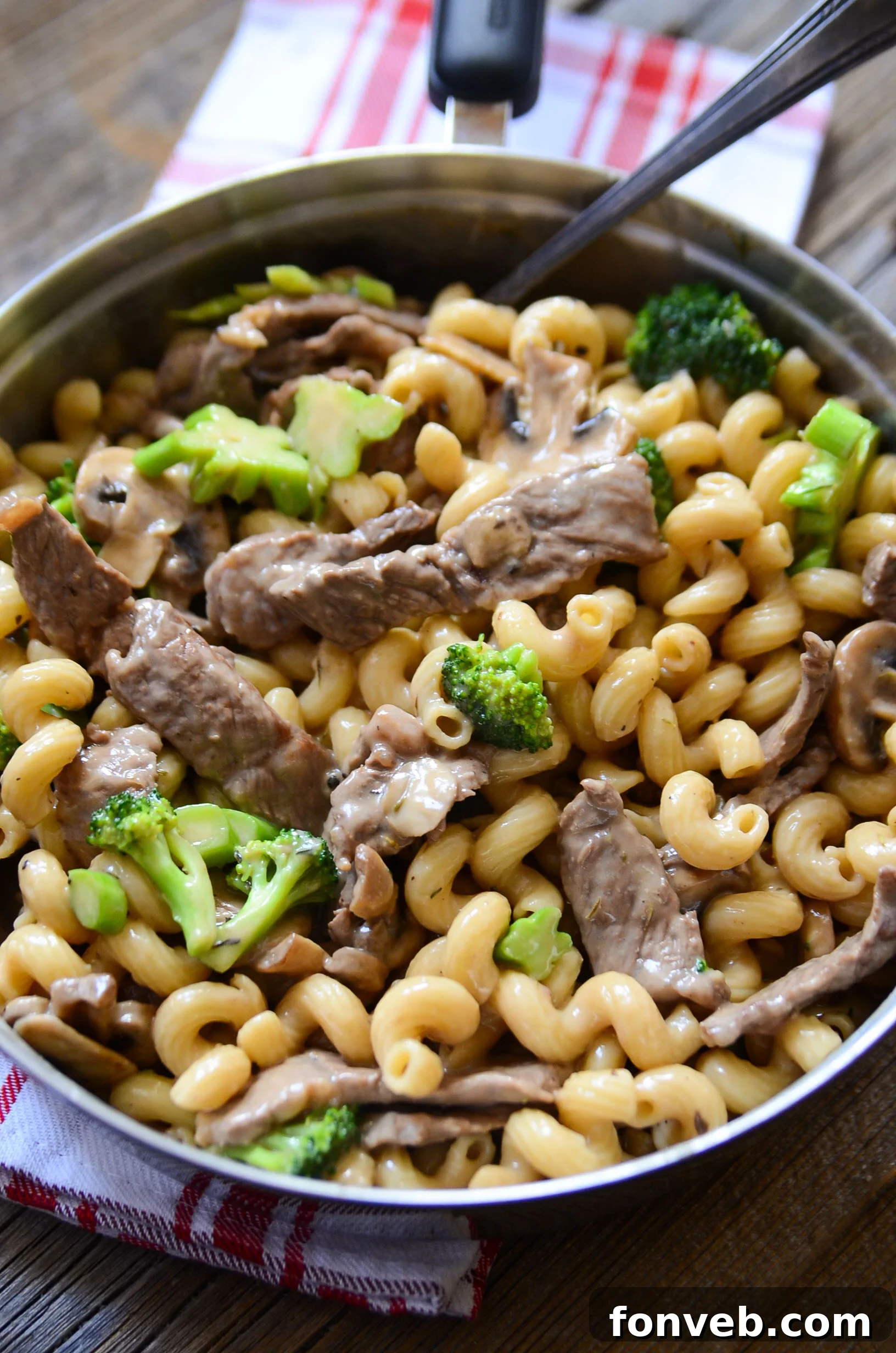 Hearty Beef, Mushroom & Broccoli Pasta 6 A person stirring the Beef, Mushroom, and Broccoli Pasta in a skillet during the cooking process.