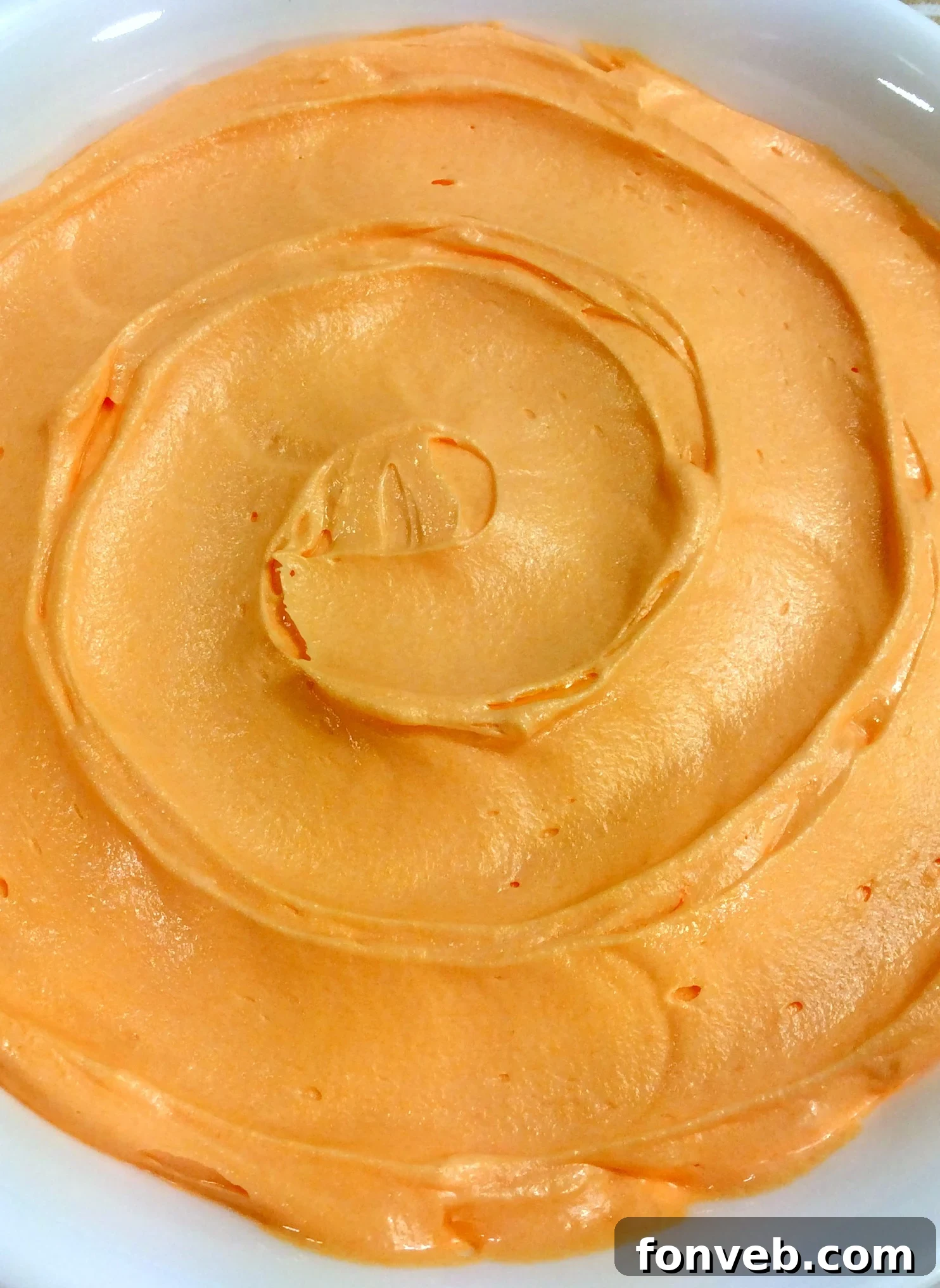 Close-up of fluffy orange creamsicle buttercream frosting swirled on a cupcake.