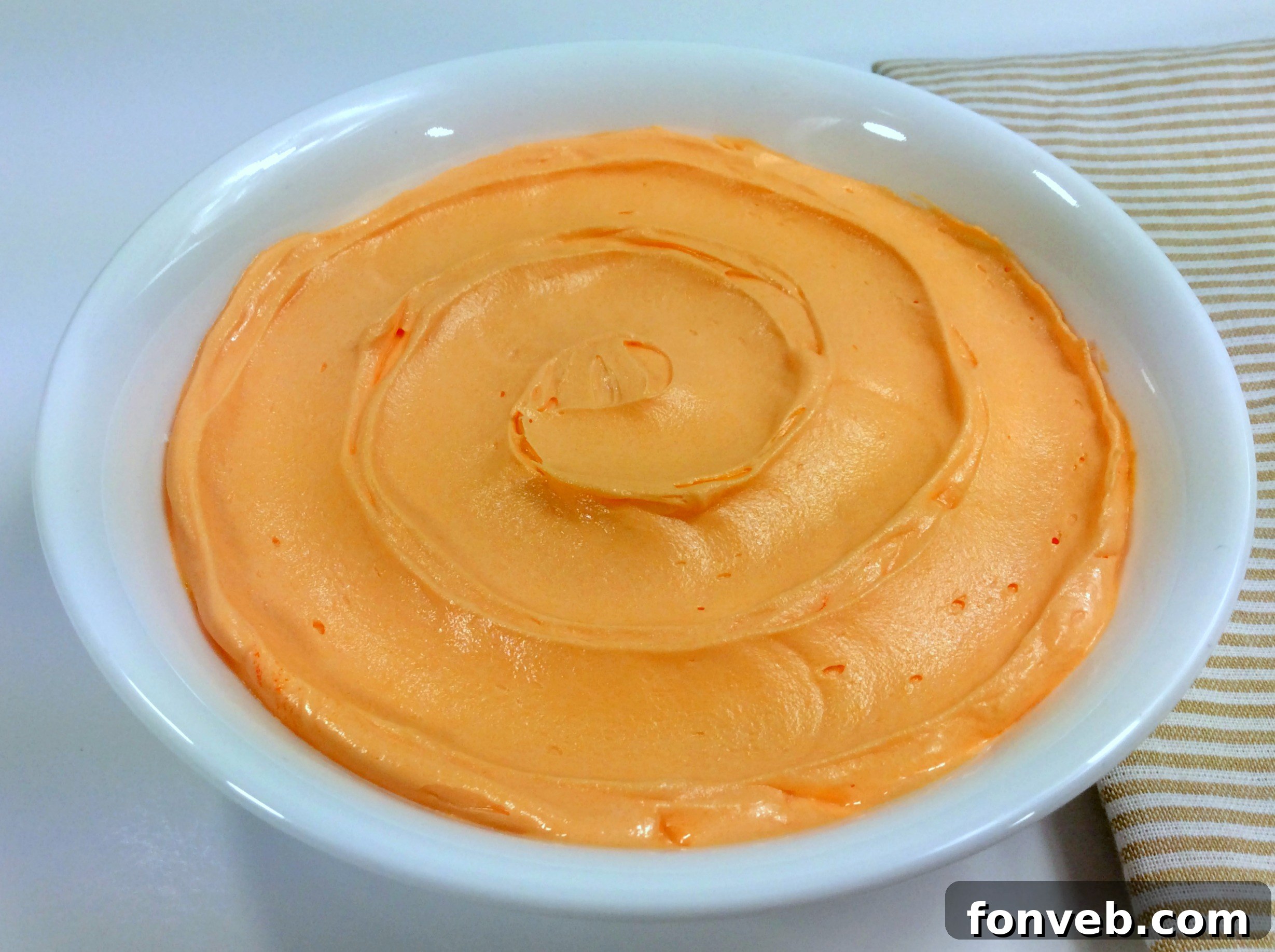 Orange creamsicle buttercream frosting in a bowl, showing its creamy texture.