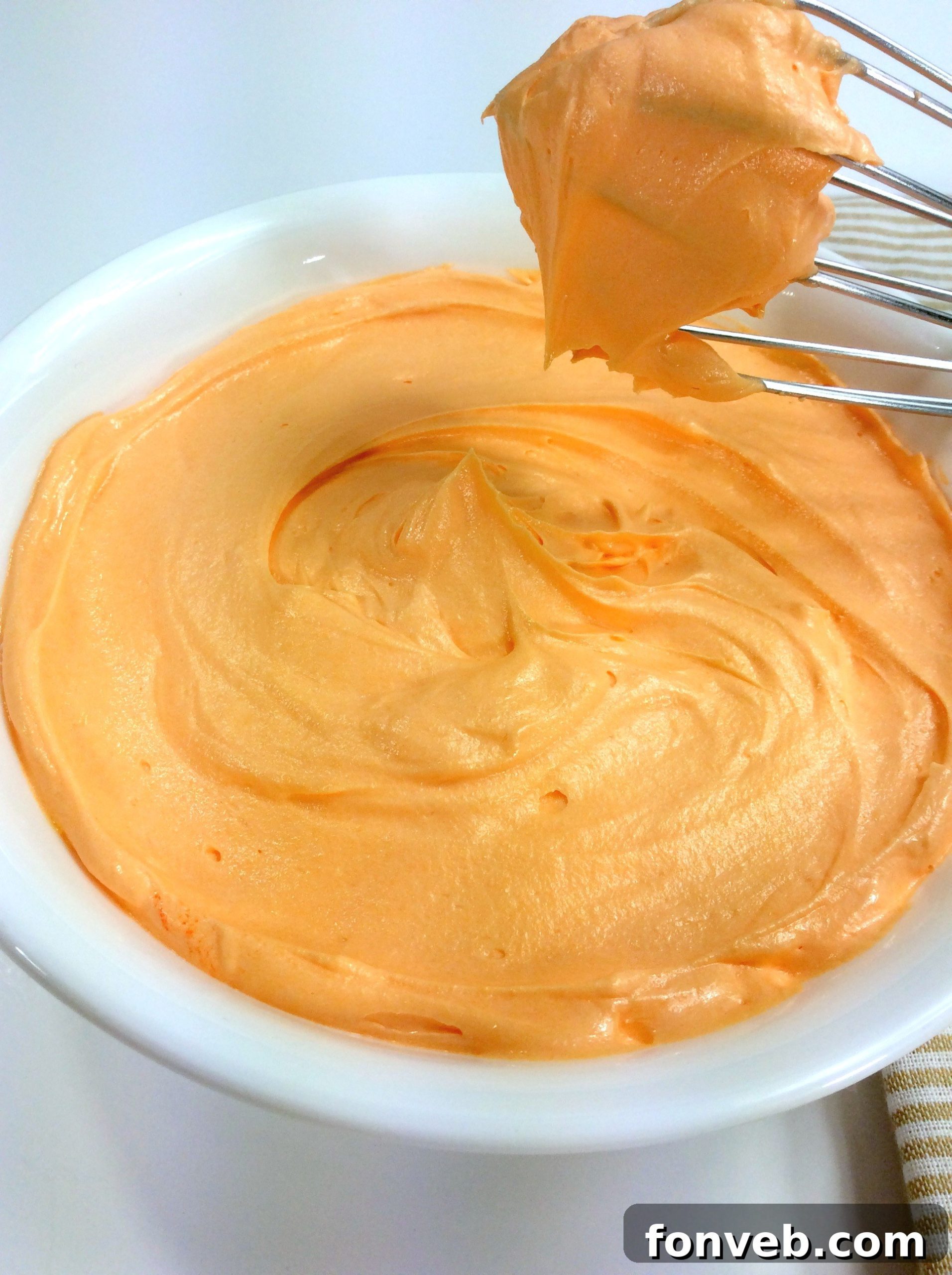 Orange creamsicle buttercream frosting piped onto a chocolate cupcake.