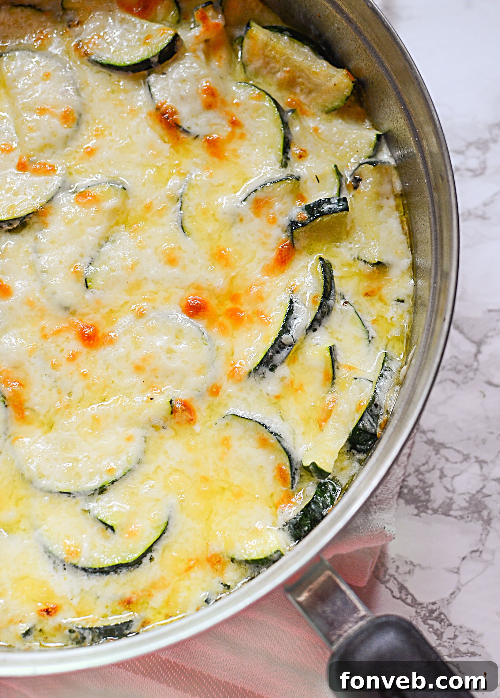 A serving of Cheesy Zucchini Gratin on a white plate, showing its creamy, textured layers