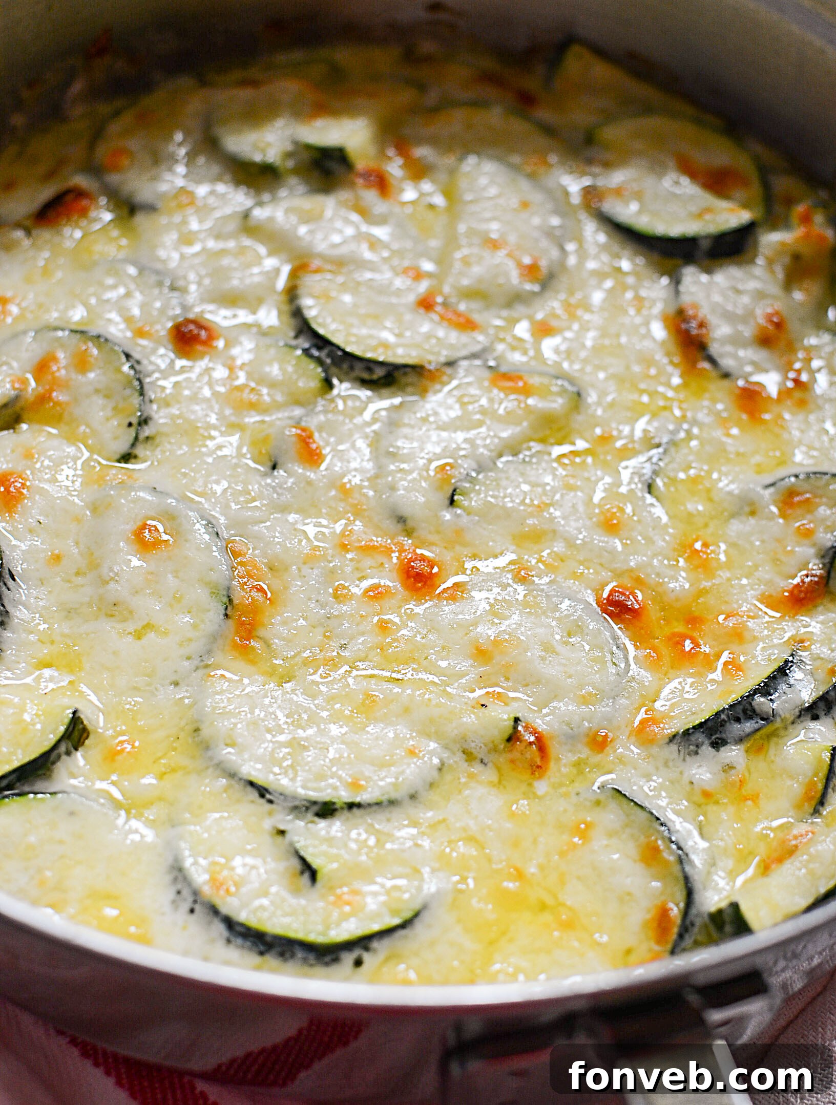 A full pan of Cheesy Zucchini Gratin, glistening with melted cheese and fresh herbs, ready to be served