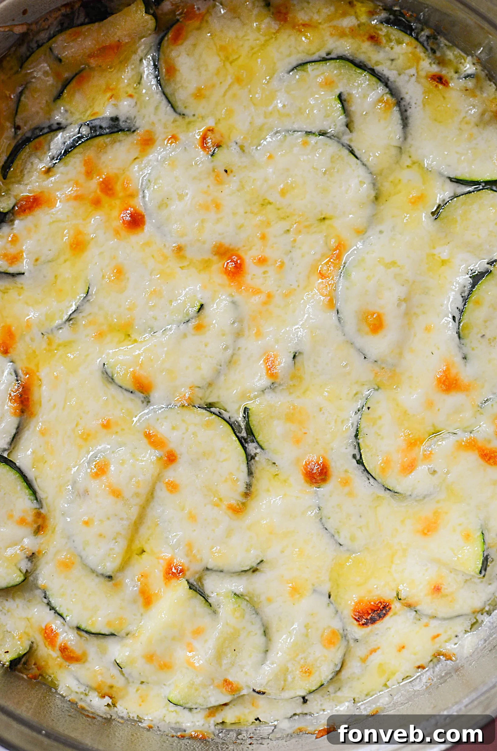 Close-up of golden Cheesy Zucchini Gratin with a mouth-watering cheese pull, emphasizing its rich texture