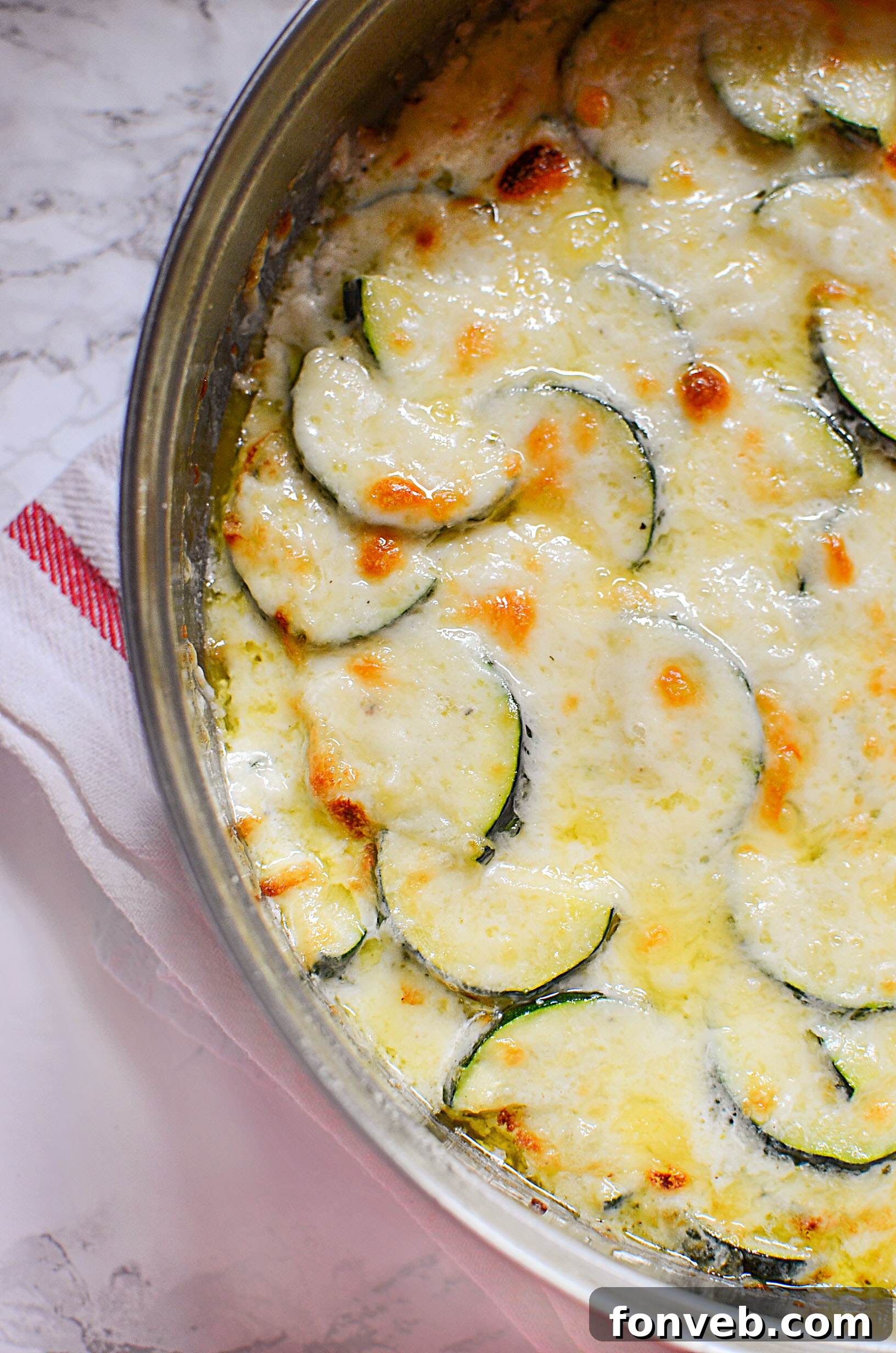 Side view of a generous portion of Cheesy Zucchini Gratin in a rectangular baking dish, ready to be served