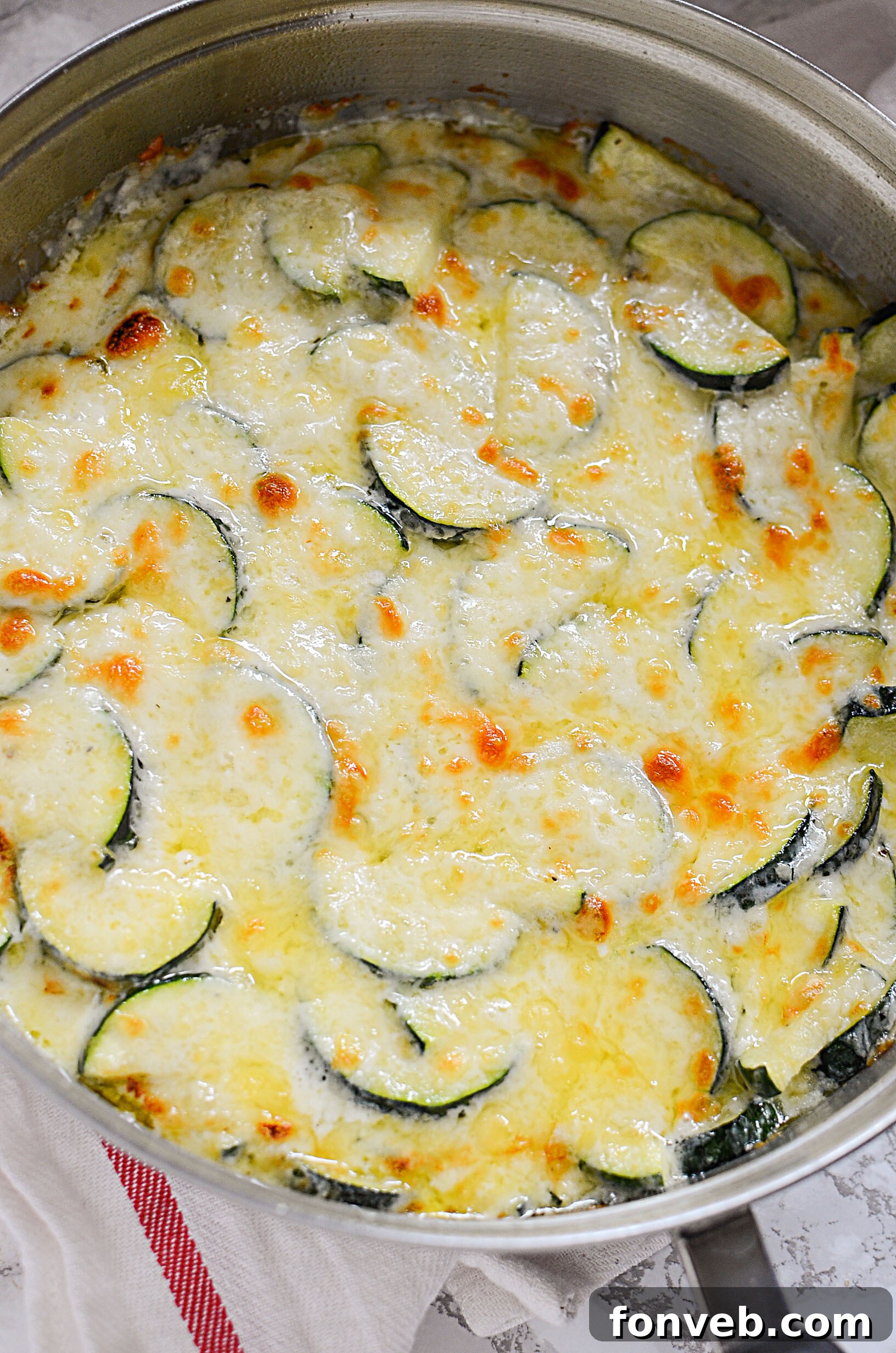 Multiple servings of hot and cheesy Zucchini Gratin in individual dishes, garnished with fresh parsley