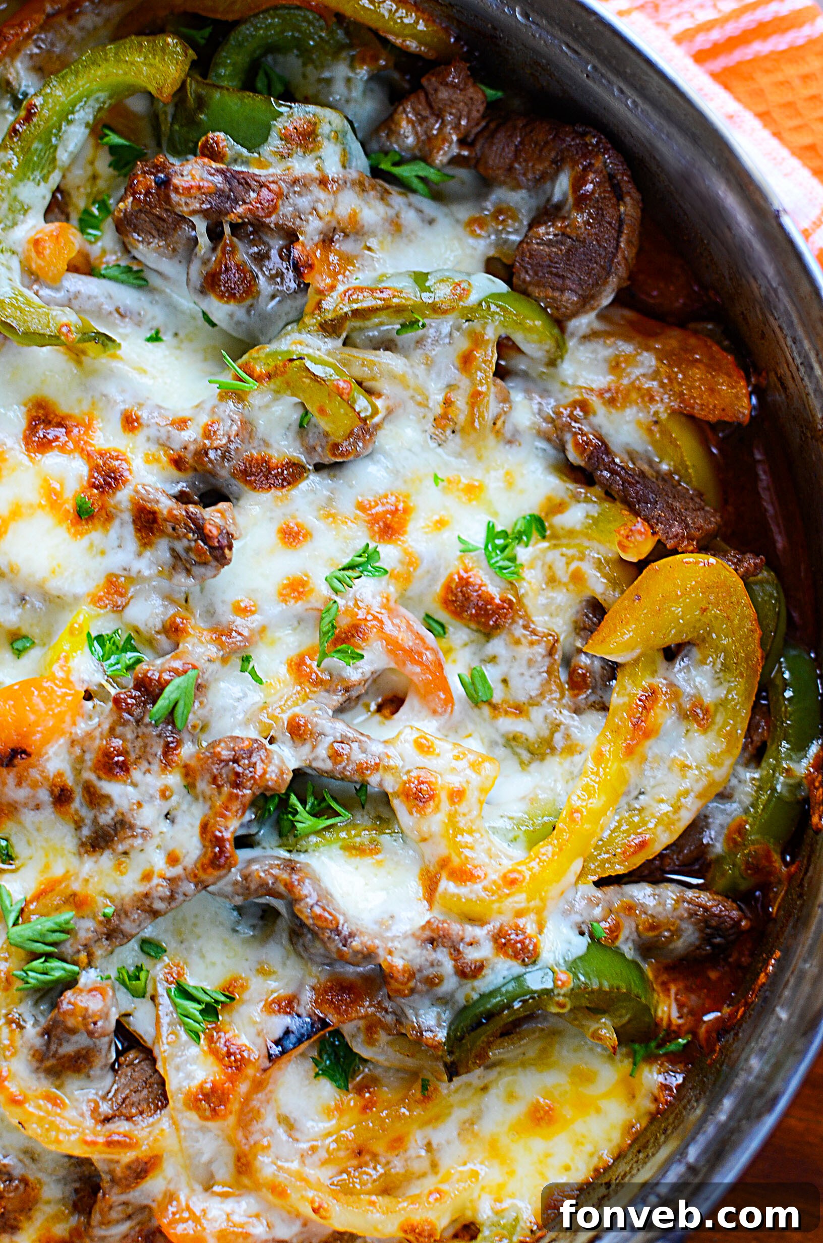 Two servings of Low Carb Philly Cheesesteak Skillet, one served plain and another on a toasted bun with a side of fries.