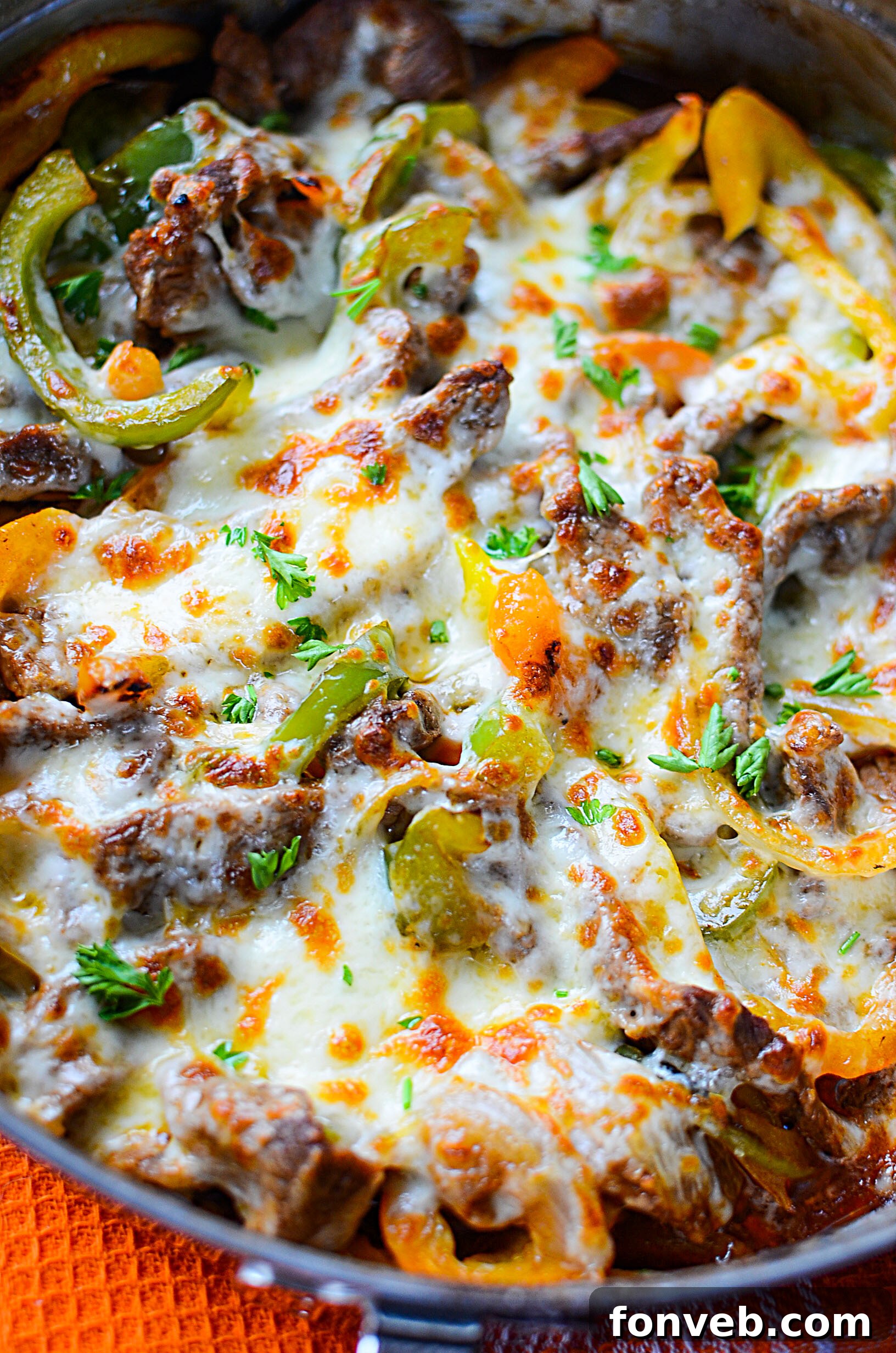 Sliced mushrooms being added to the cooking skillet with steak, onions, and peppers for extra flavor.