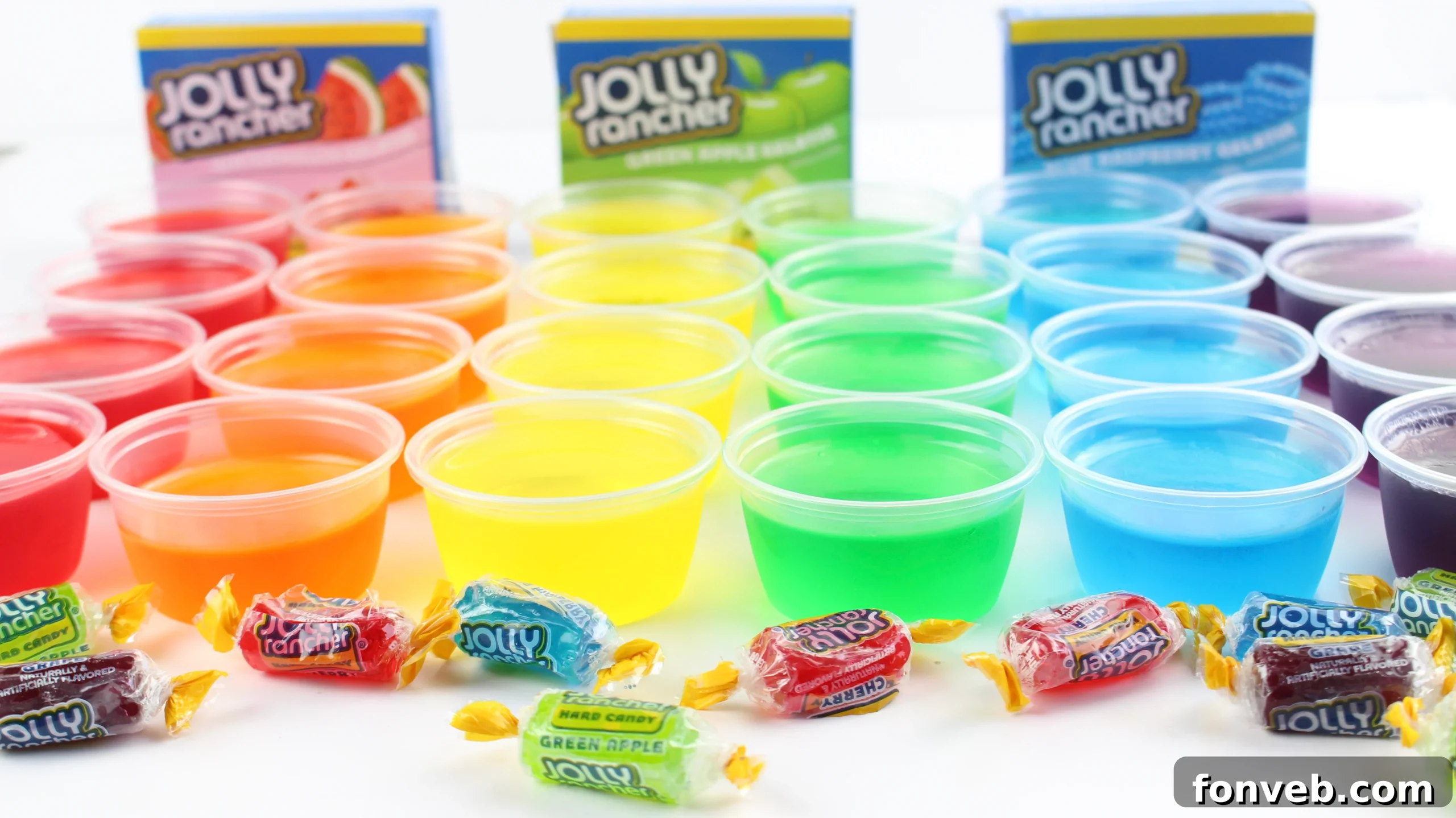 A colorful array of Jolly Rancher Jello Shots, featuring red, green, blue, and purple gelatin in small plastic cups, ready for a party.