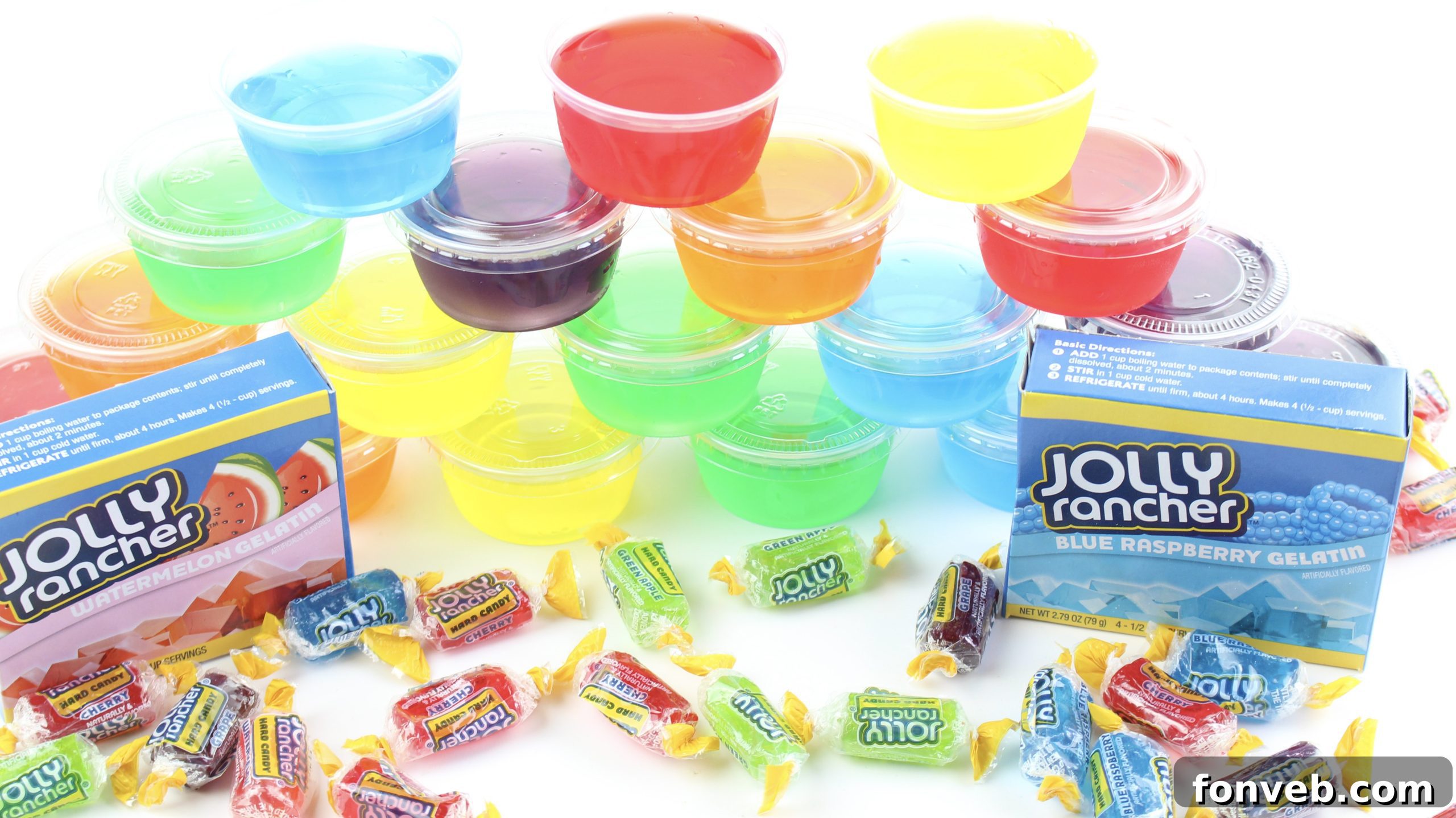An overhead shot of an assortment of colorful Jello shots in clear plastic cups on a white surface.