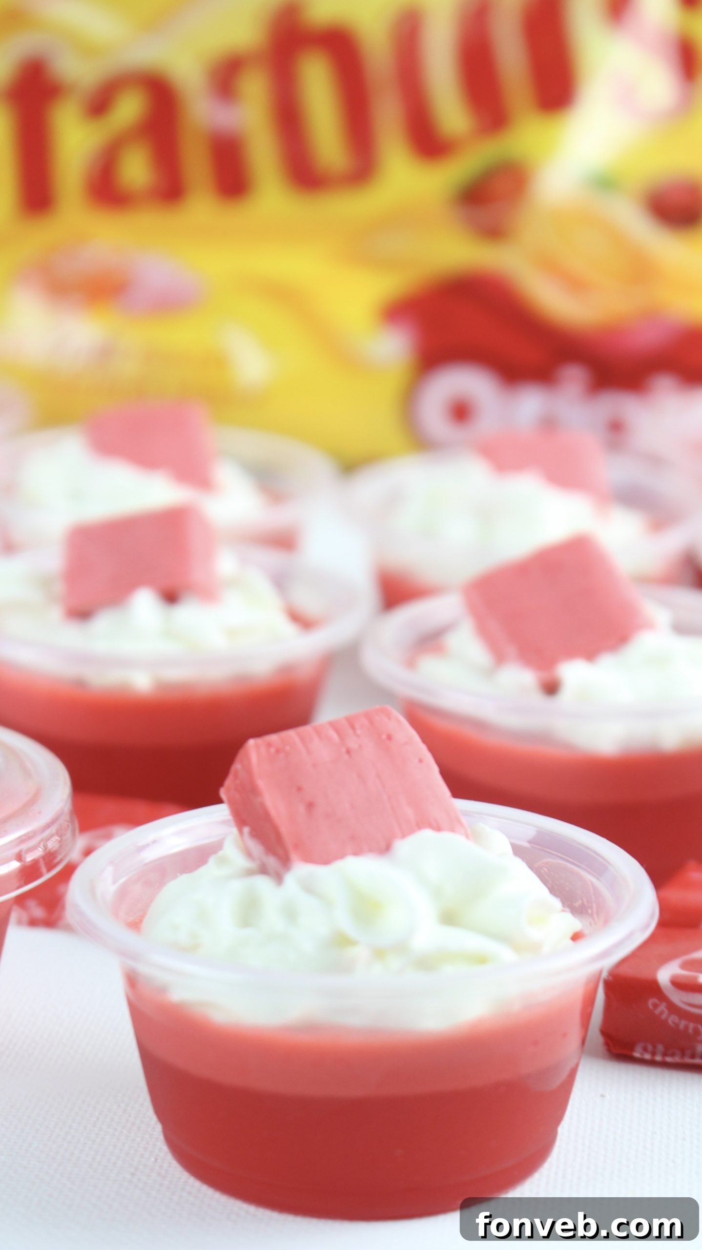 A vibrant Pink Starburst cocktail next to a tray of Cherry Starburst Jell-O Shots, inviting readers to explore related recipes.