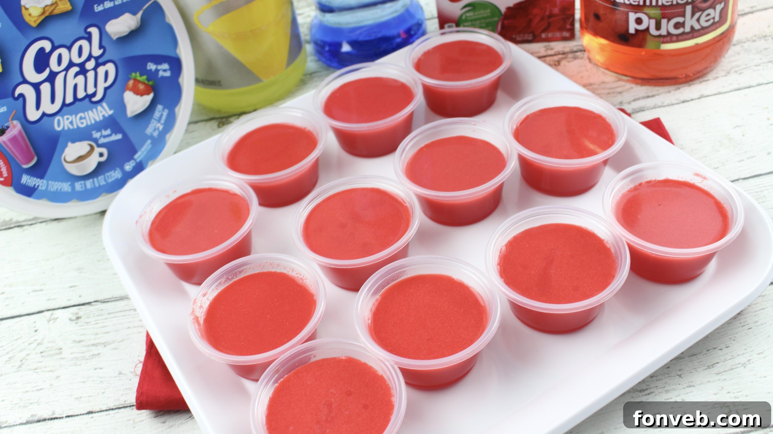 Multiple Cherry Starburst Jell-O Shots displayed neatly on a white surface, showcasing their vivid color.