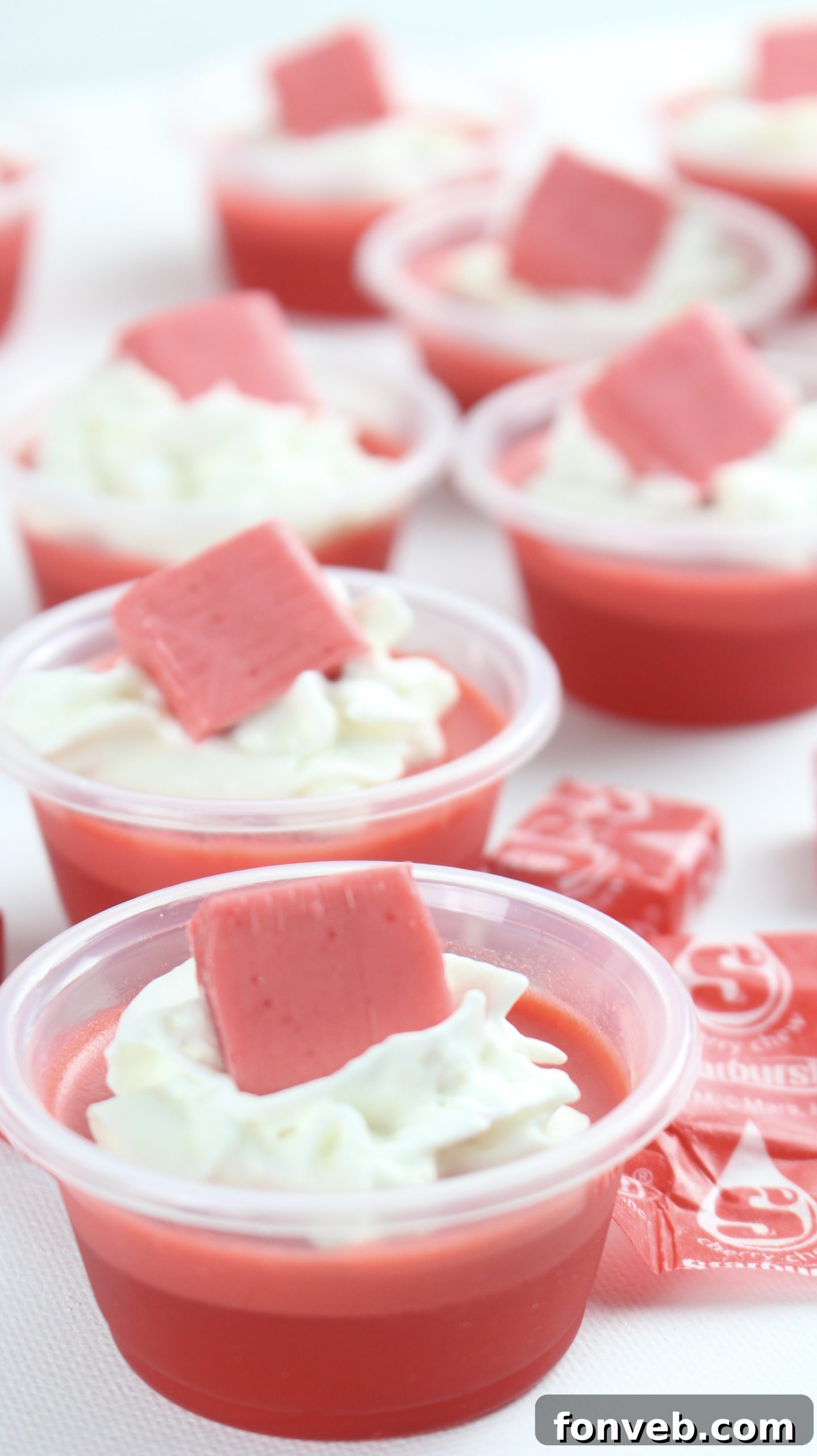An array of Cherry Starburst Jell-O Shots beautifully presented on a wooden board.