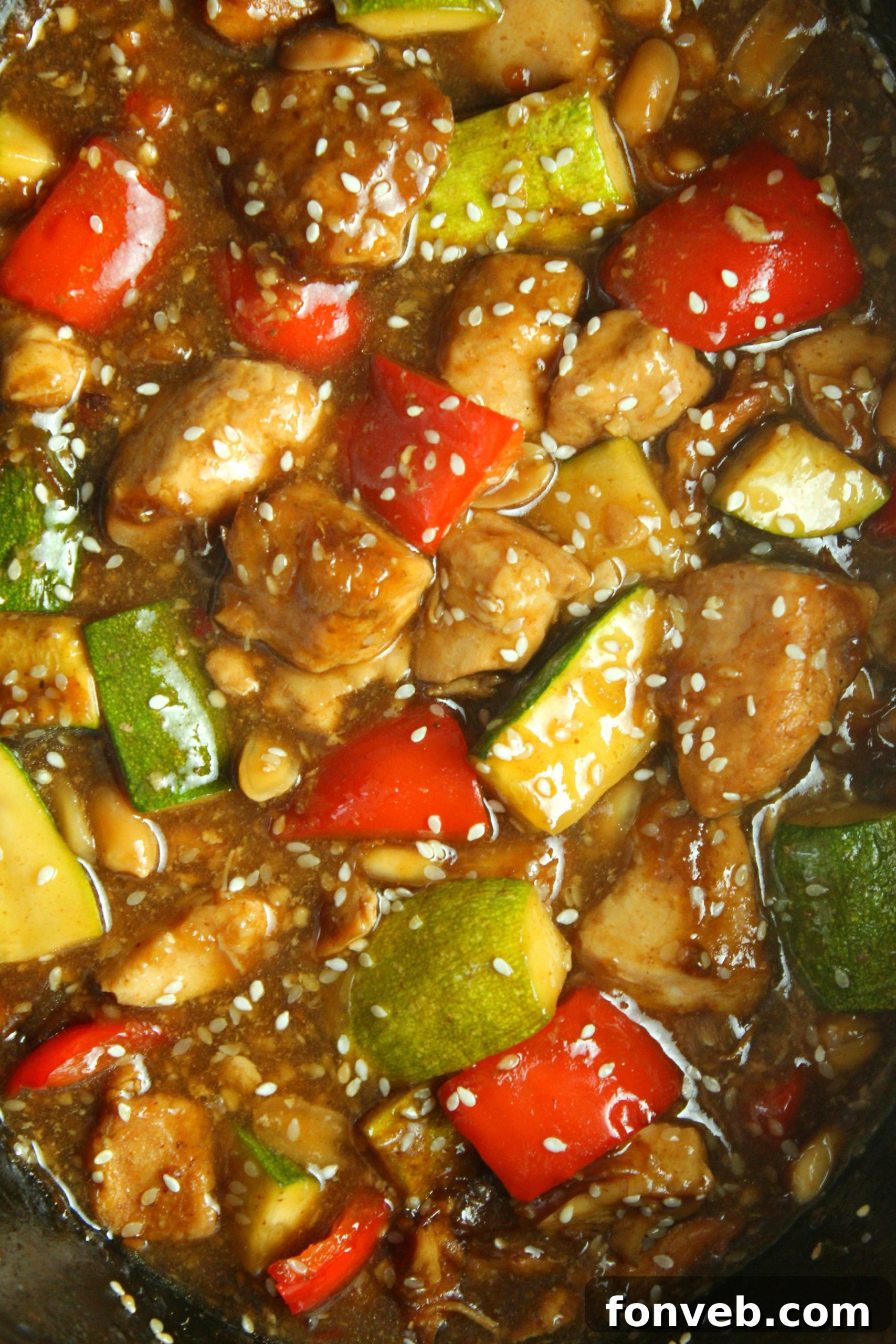 A bowl of Slow Cooker Kung Pao Chicken garnished with green onions and sesame seeds.