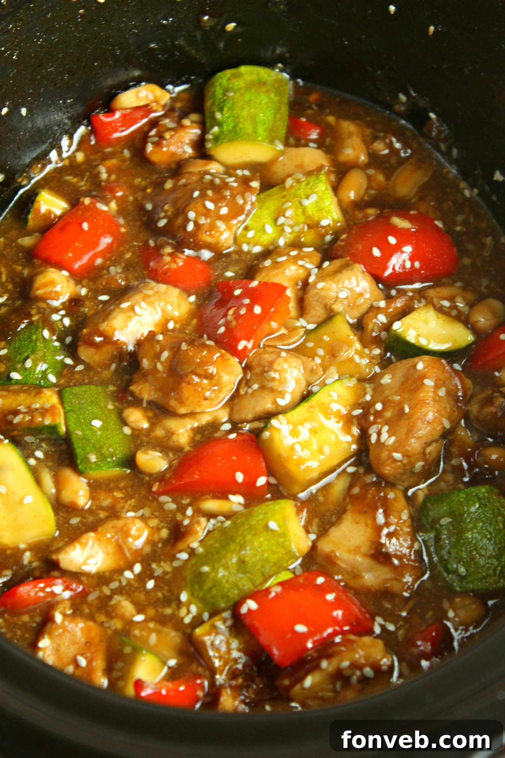 A serving of Slow Cooker Kung Pao Chicken over a bed of white rice with chopsticks.