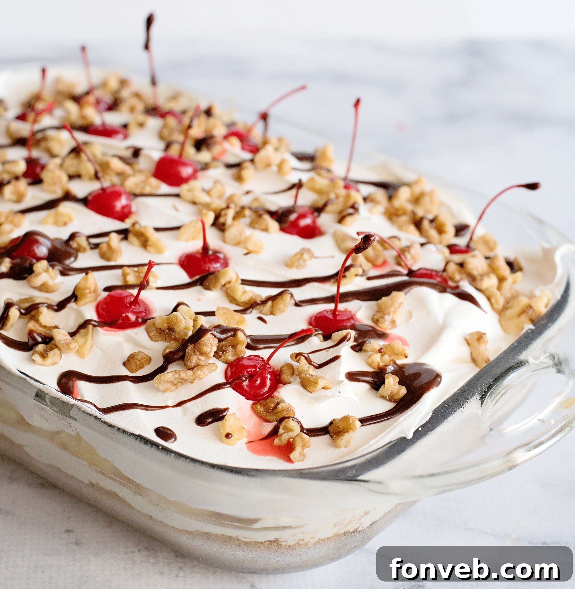 No Bake Banana Split Dream 6 No-Bake Banana Split Dessert, garnished with a generous amount of hot fudge, walnuts, and cherries, ready to be served.