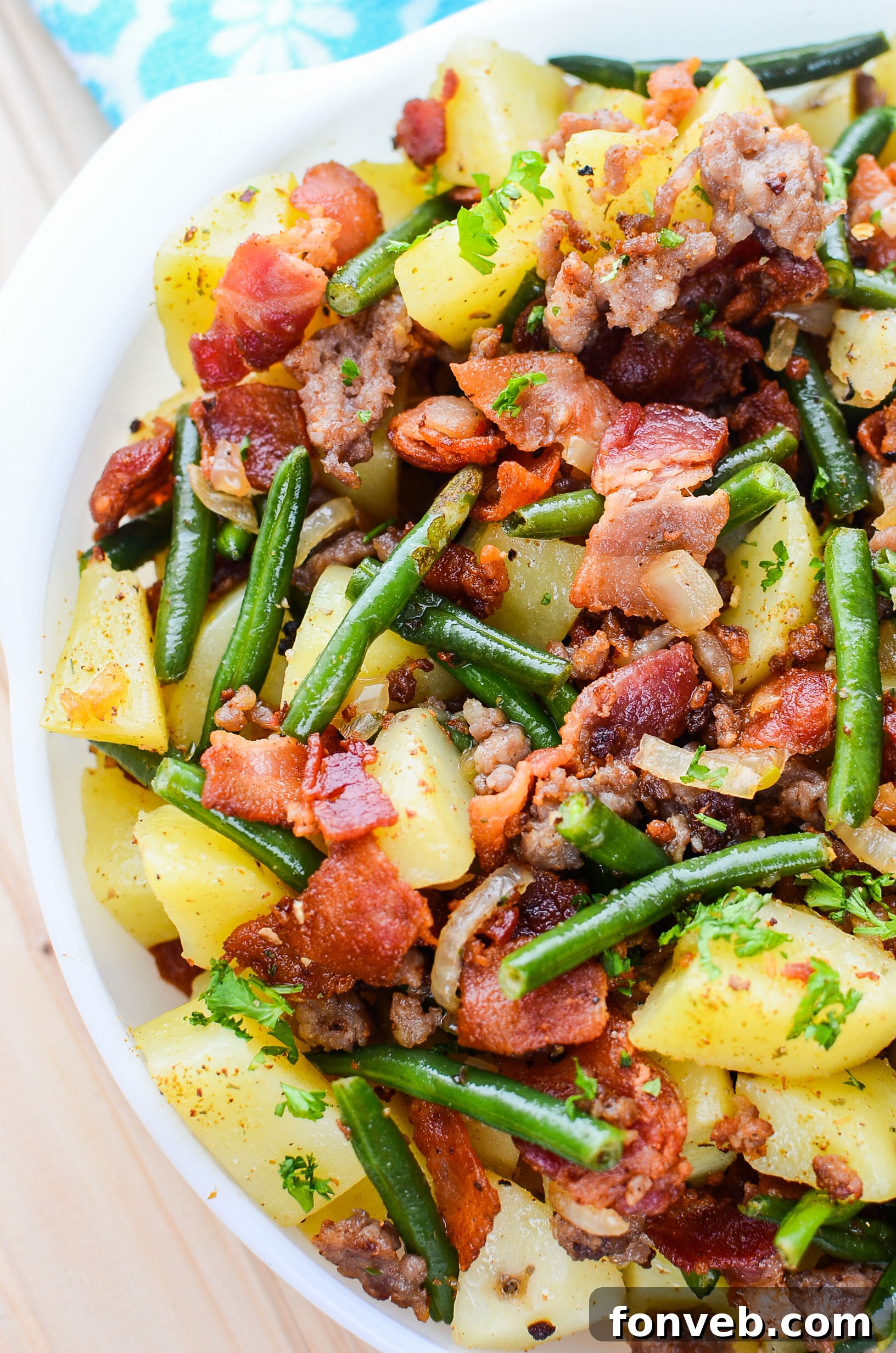 A close-up shot of the cooked Southern Sausage, Potatoes, and Green Beans, emphasizing the well-browned bacon.