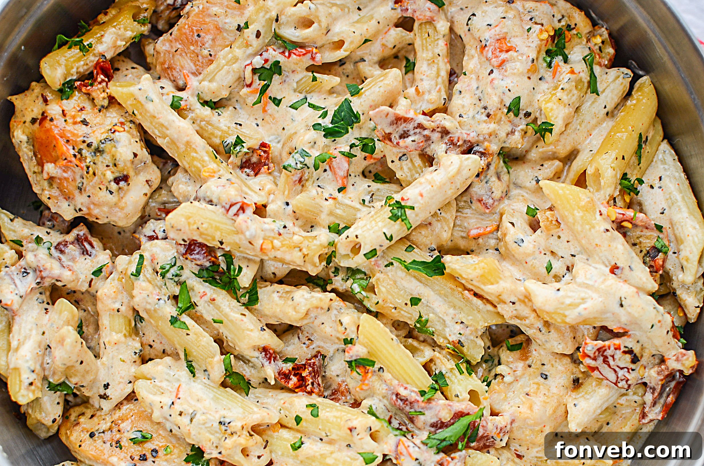 Overhead view of the finished creamy sun dried tomato chicken pasta in a skillet, ready to be served.