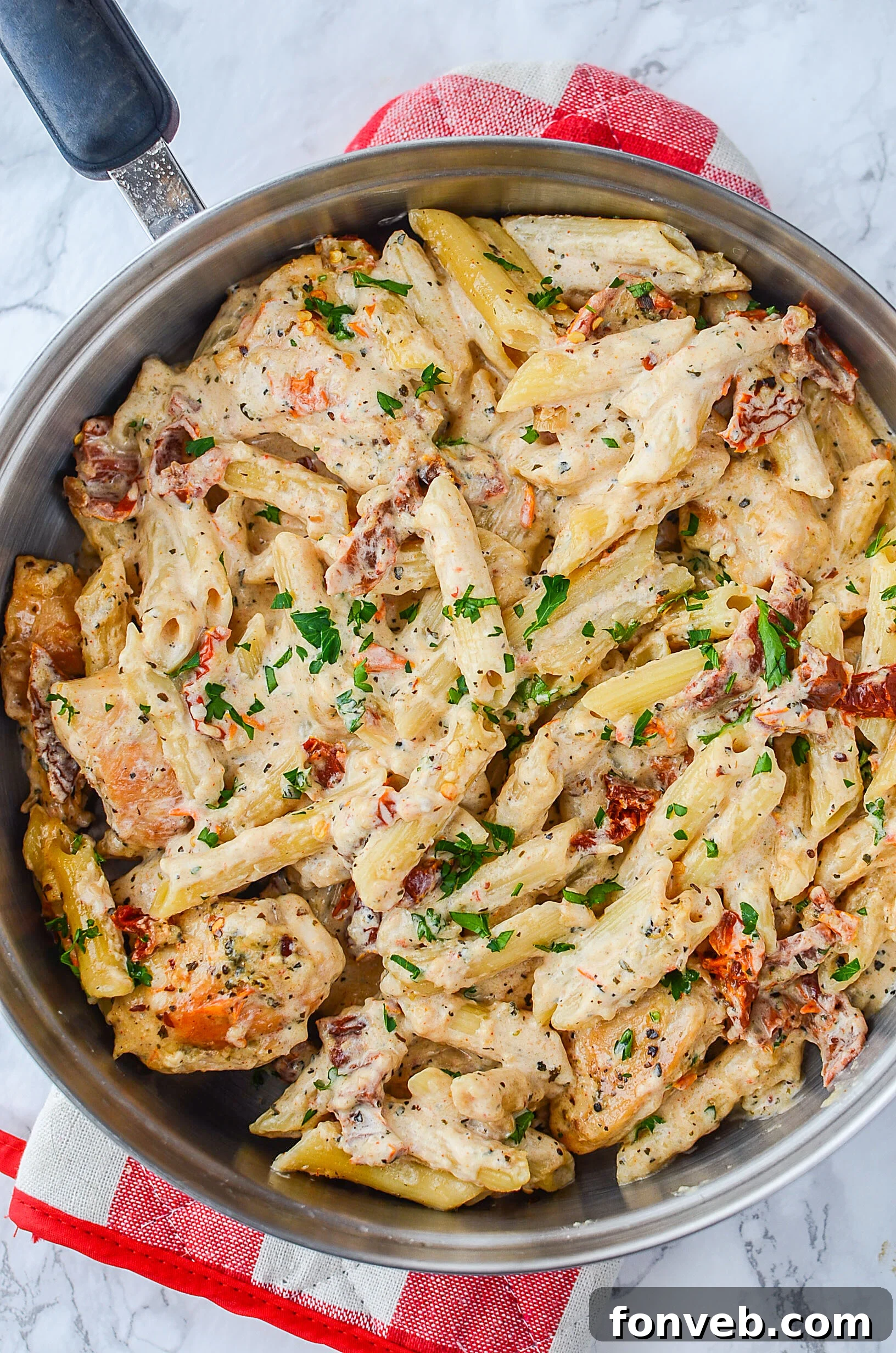 Close-up shot of the creamy sun dried tomato chicken pasta in a skillet, showcasing the rich sauce and chicken.