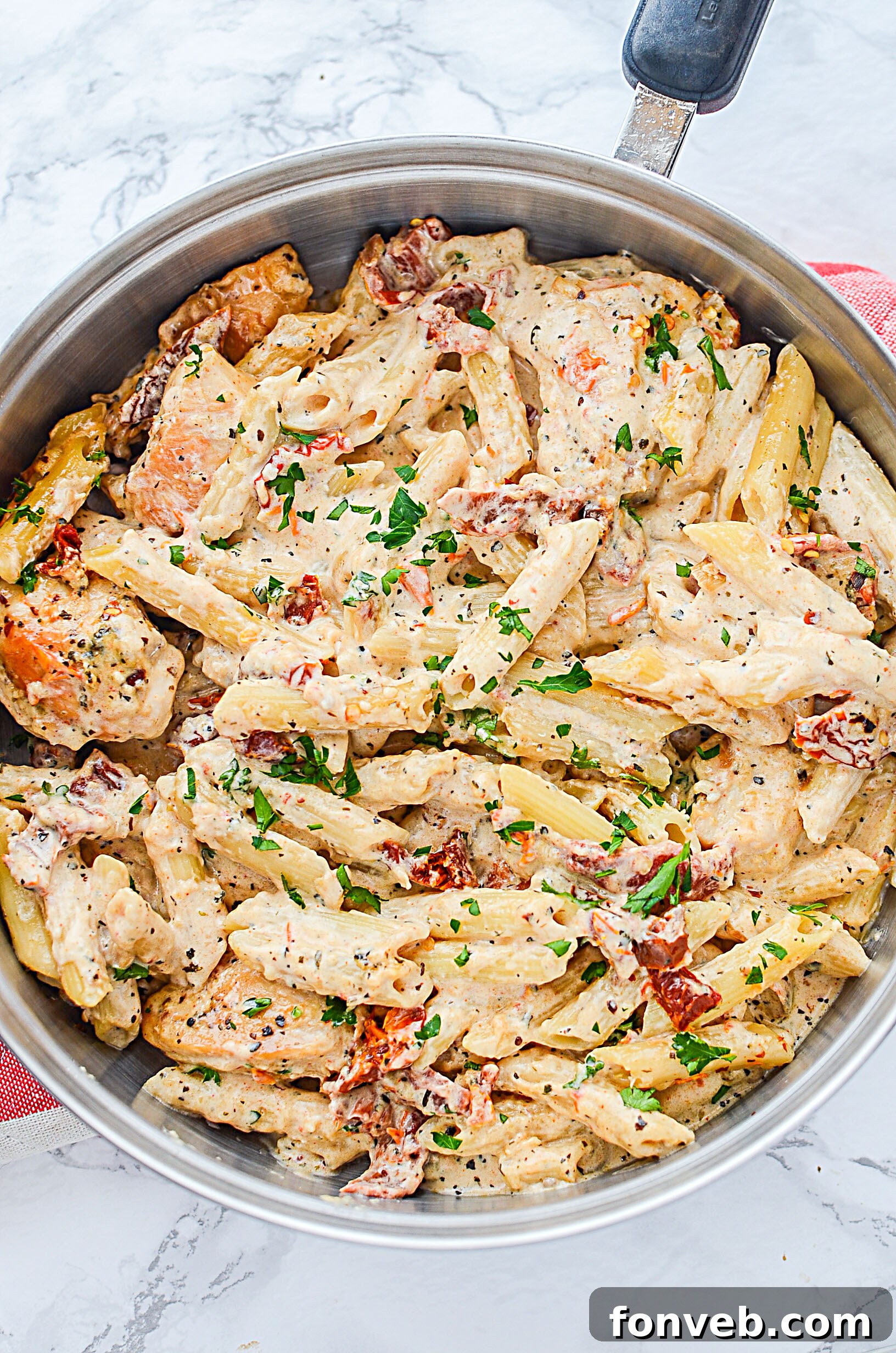 A vibrant close-up of sun dried tomato chicken pasta showing the detailed texture of the sauce and chicken.