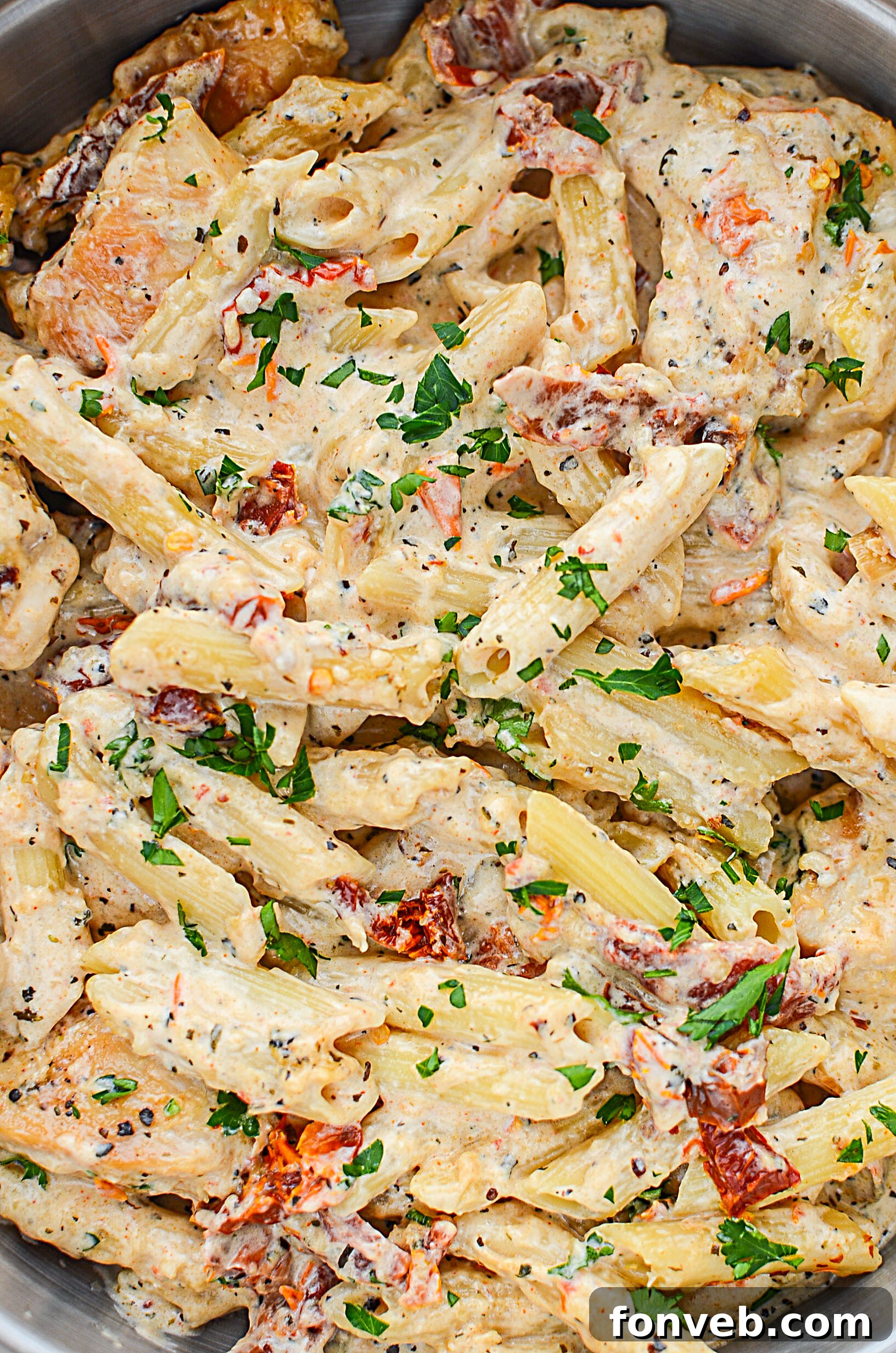 A generous serving of creamy sun dried tomato chicken pasta on a rustic plate.