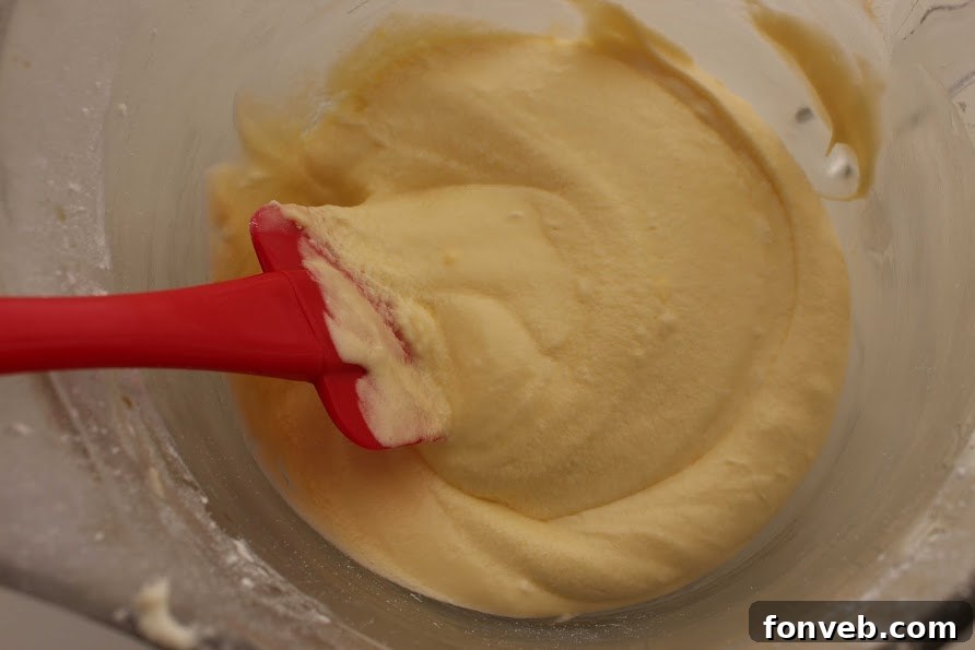 The pineapple whipped topping being spread on the creamy layer