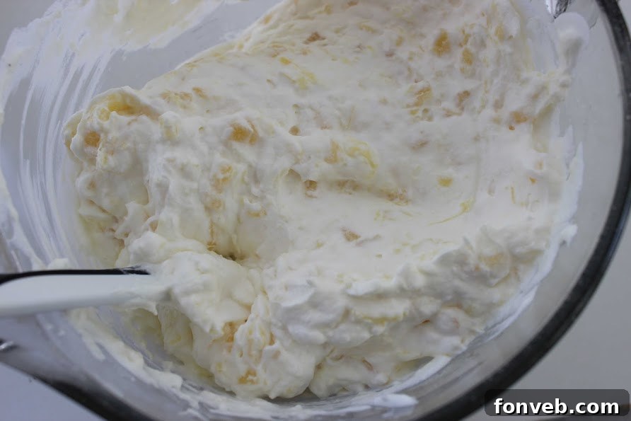 Finished pineapple lush dessert topped with a fluffy whipped cream and pineapple mixture