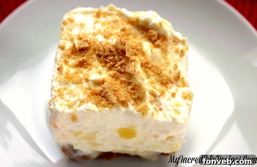 A square pan of pineapple lush dessert, garnished with graham cracker crumbs