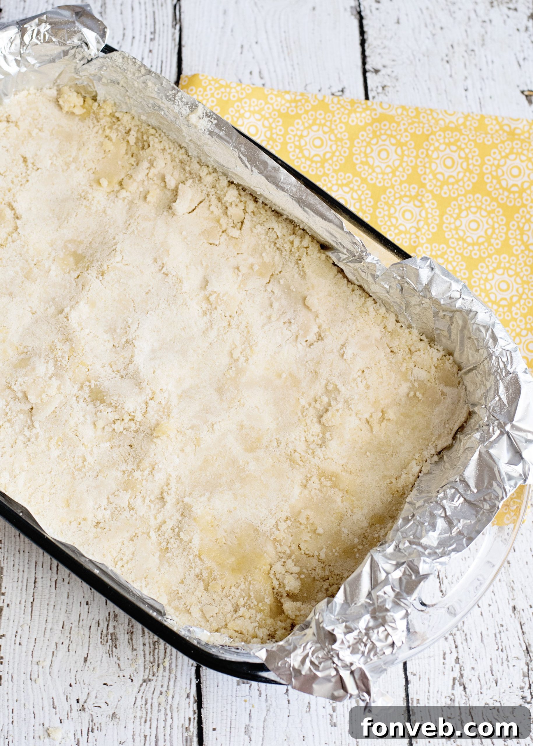 Two rows of freshly baked Ooey Gooey Butter Bars in a baking dish, glistening with their signature gooey top layer.