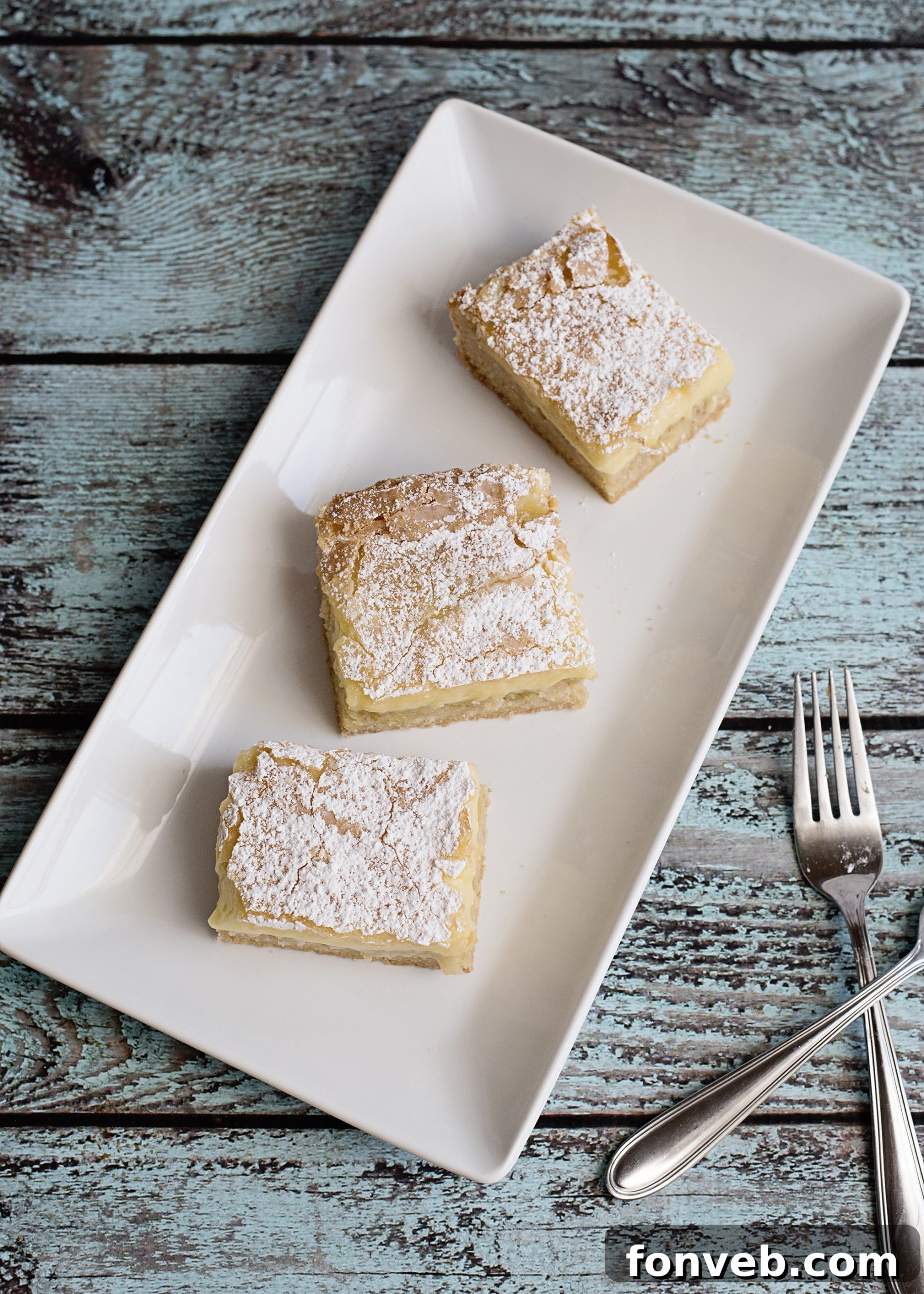 A close-up shot of a gooey butter bar, showcasing its rich, golden-brown crust and smooth, pale top layer.