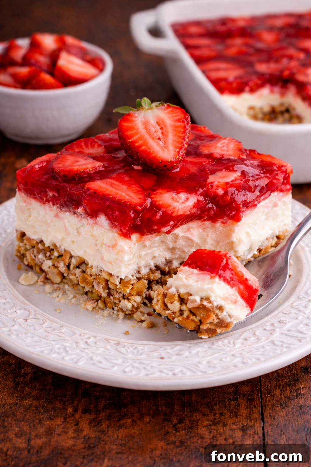 Strawberry Pretzel Salad on a pretty white plate with a fork taking a bite out of the slice