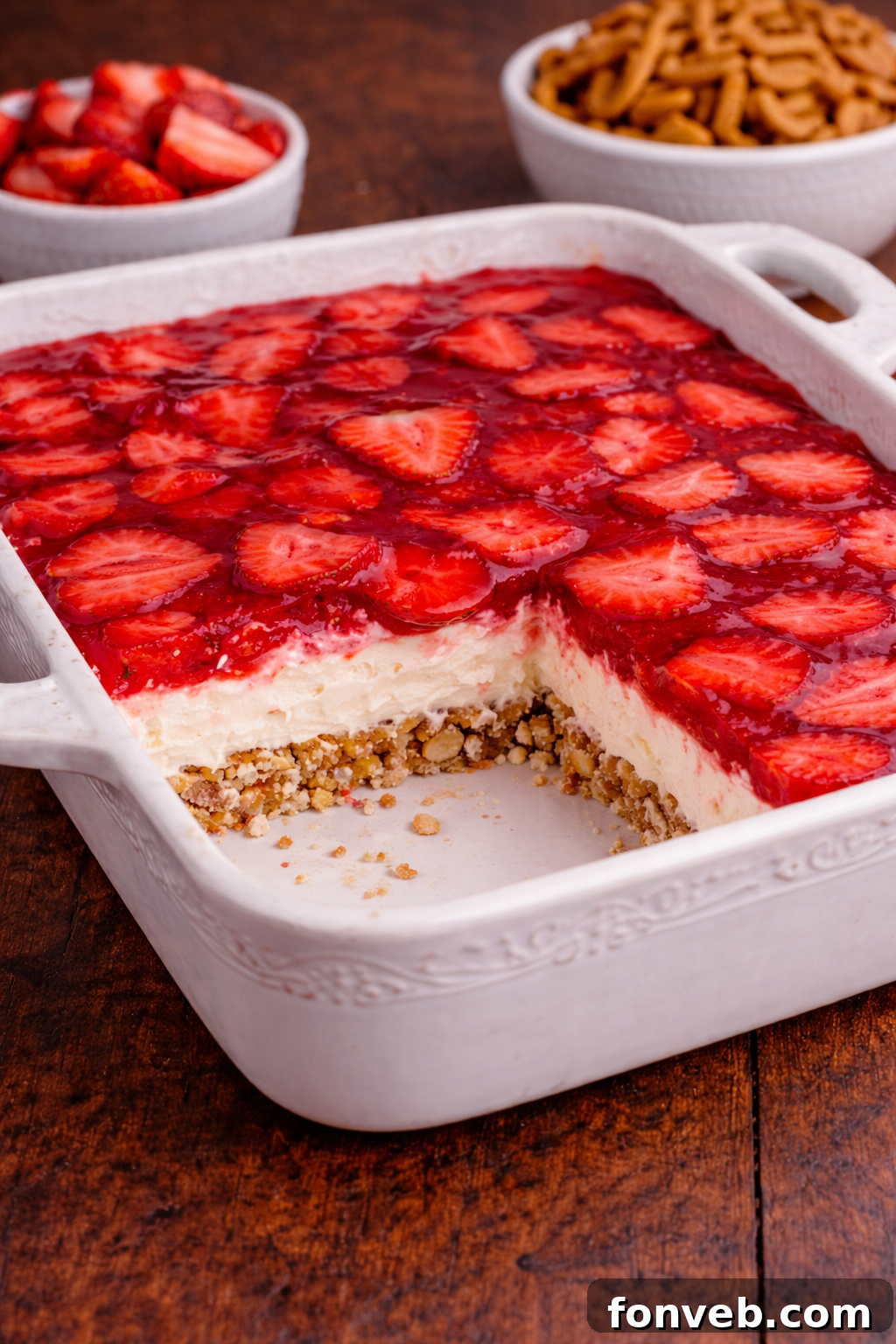 Strawberry Pretzel Salad in a pretty white baking pan with a slice missing 