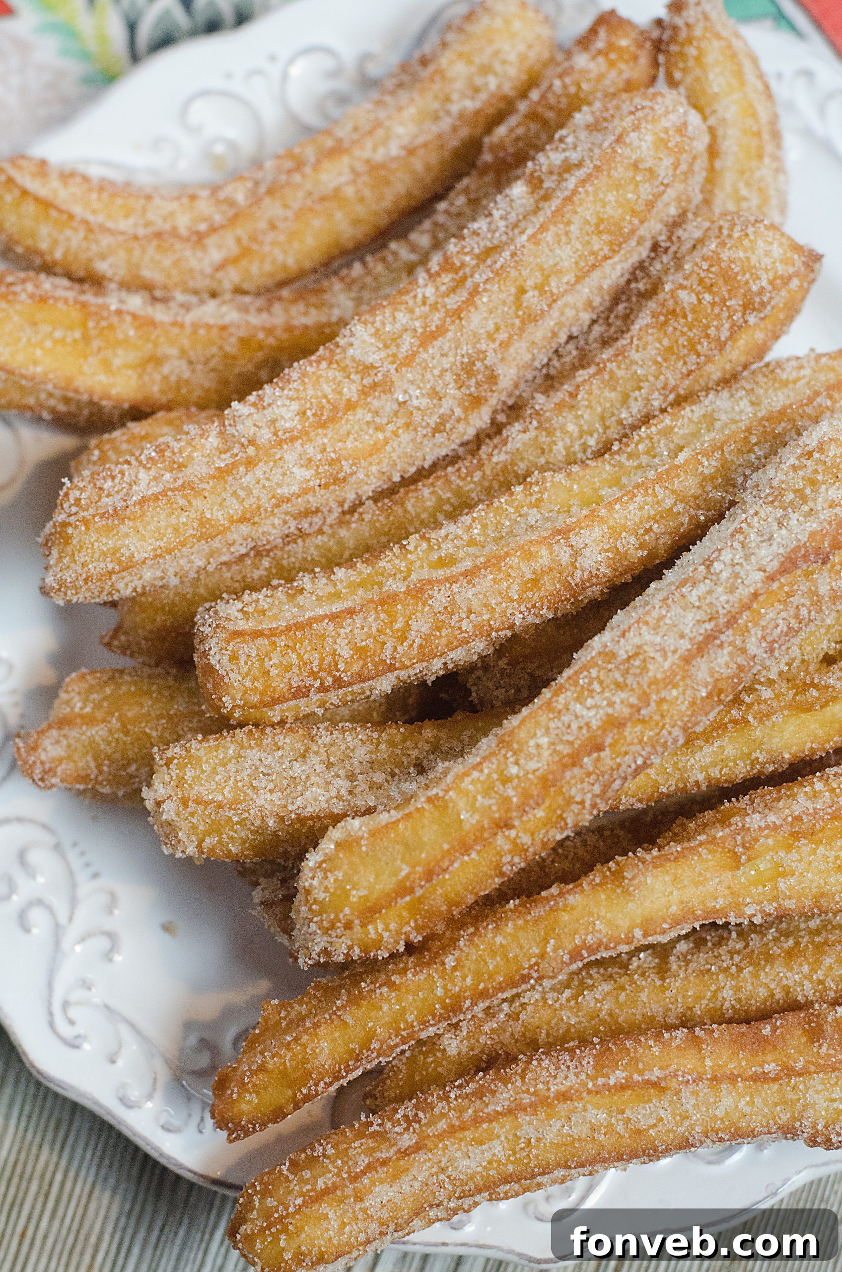 Golden brown homemade churros stacked on a plate