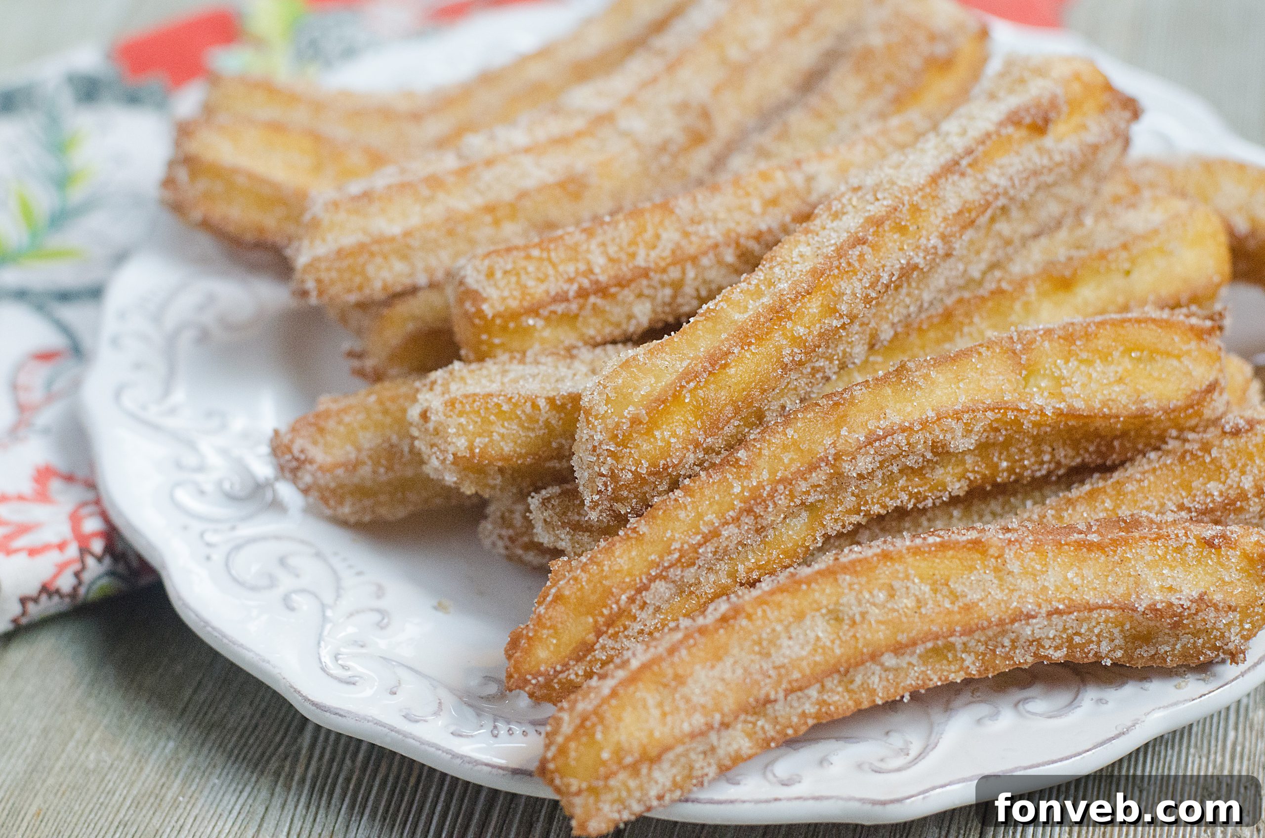 Freshly fried churros being coated in cinnamon sugar