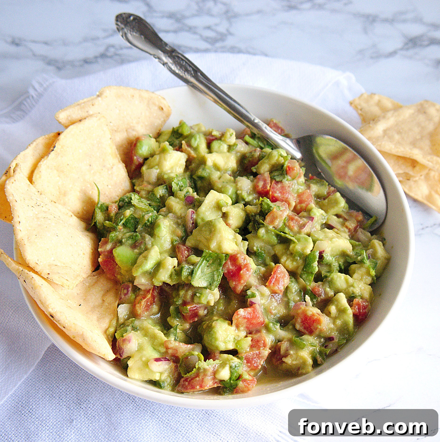 A beautifully textured bowl of homemade chunky guacamole with fresh ingredients visible.