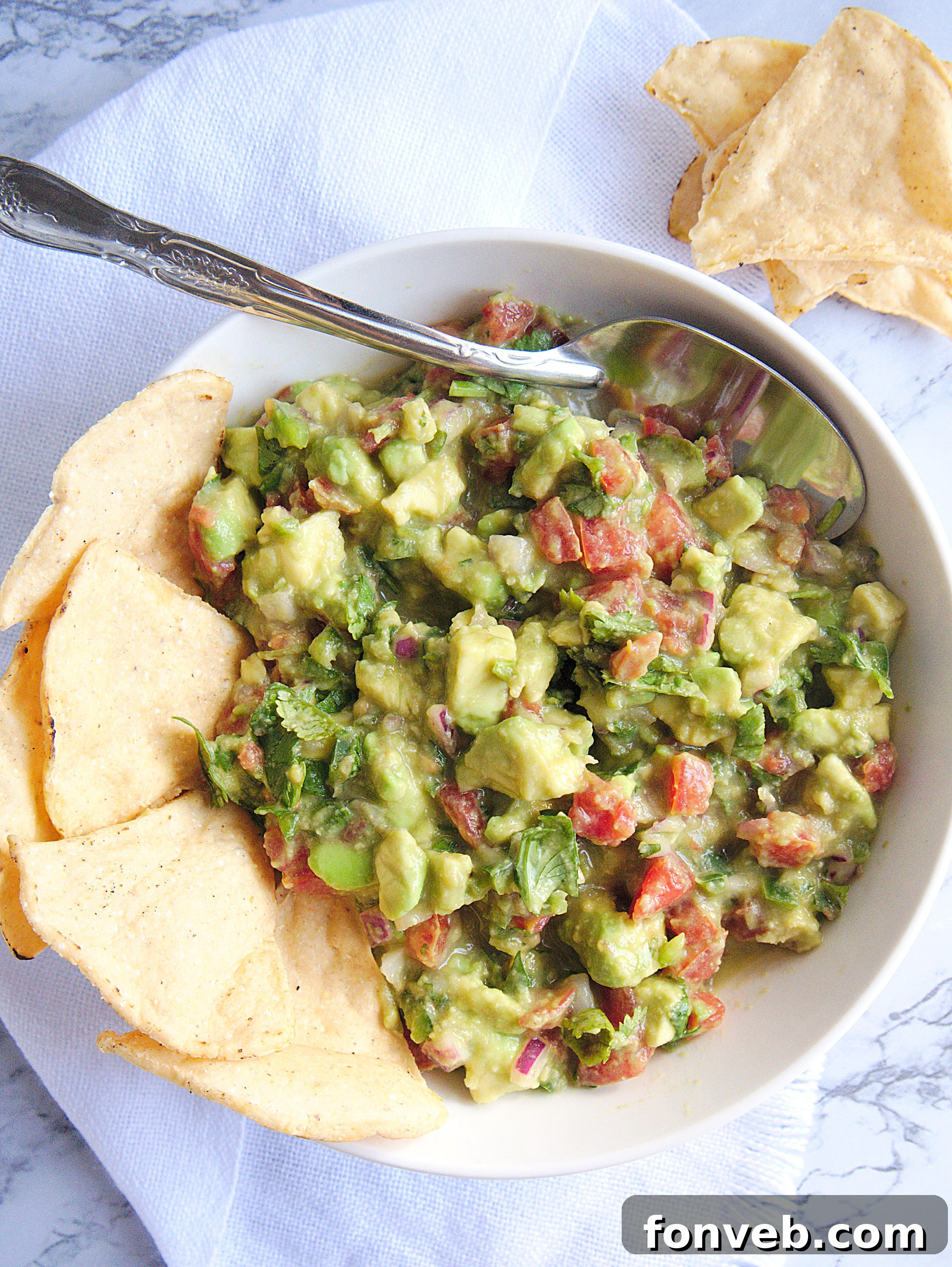 A visually appealing shot of freshly made chunky guacamole with a focus on its ingredients and texture.